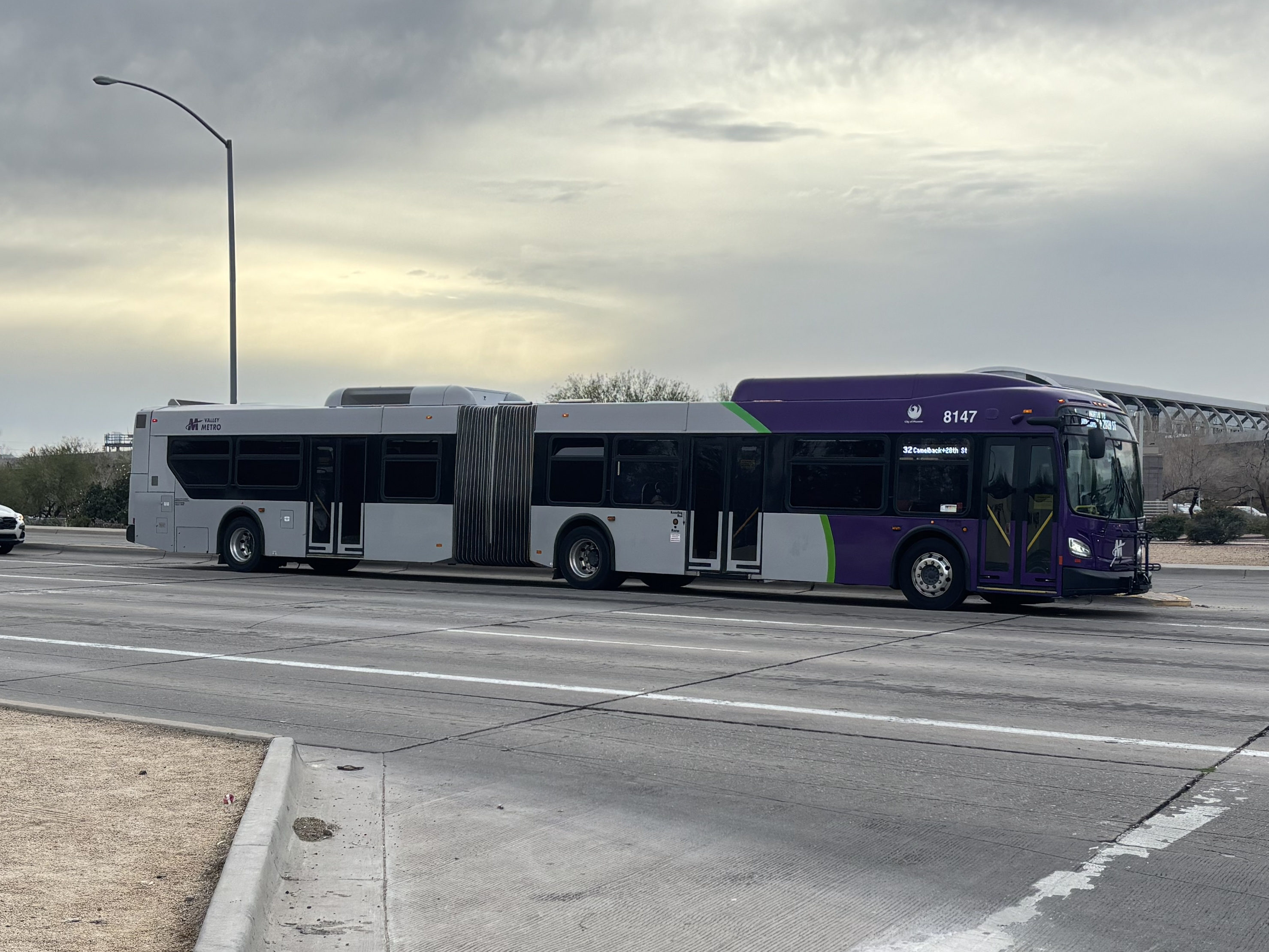 A purple and gray articulated Valley Metro bus, number 8147, traveling northbound on 44th Street in Phoenix on route 32 to Camelback Road and 28th Street