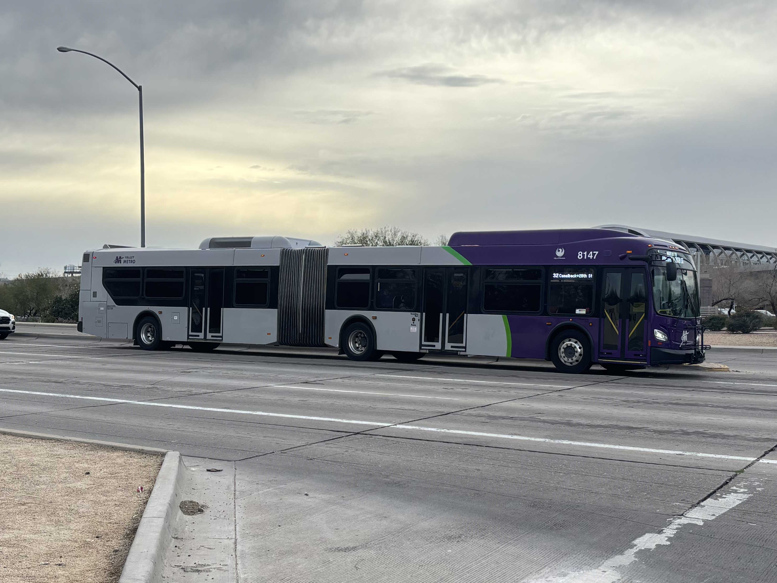 A purple and gray articulated Valley Metro bus, number 8147, traveling northbound on 44th Street in Phoenix on route 32 to Camelback Road and 28th Street