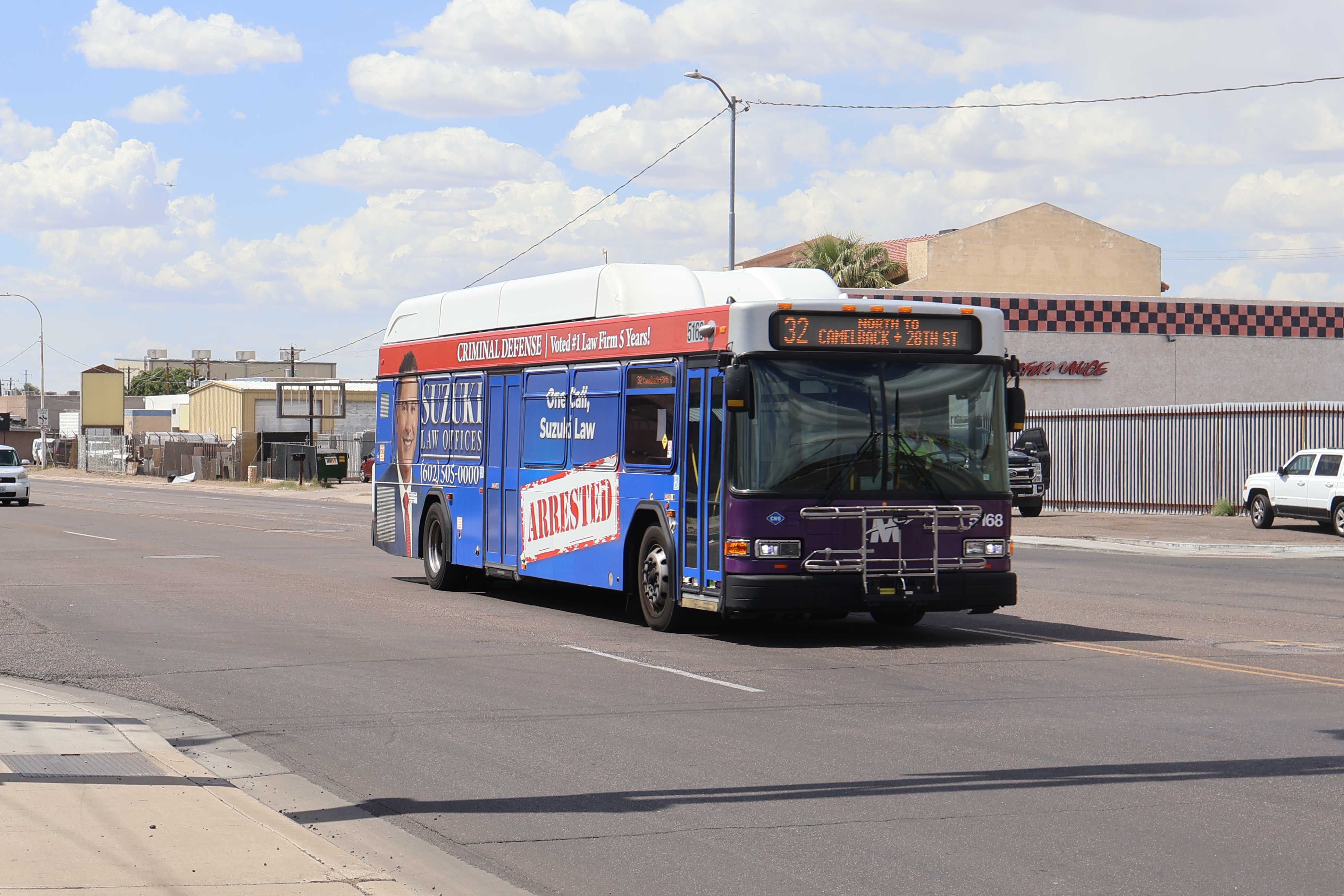 A white and gray Valley Metro bus, with purple and green accent colors, number 5168, traveling eastbound on University Drive in Phoenix on route 32 to Camelback Road and 28th Street