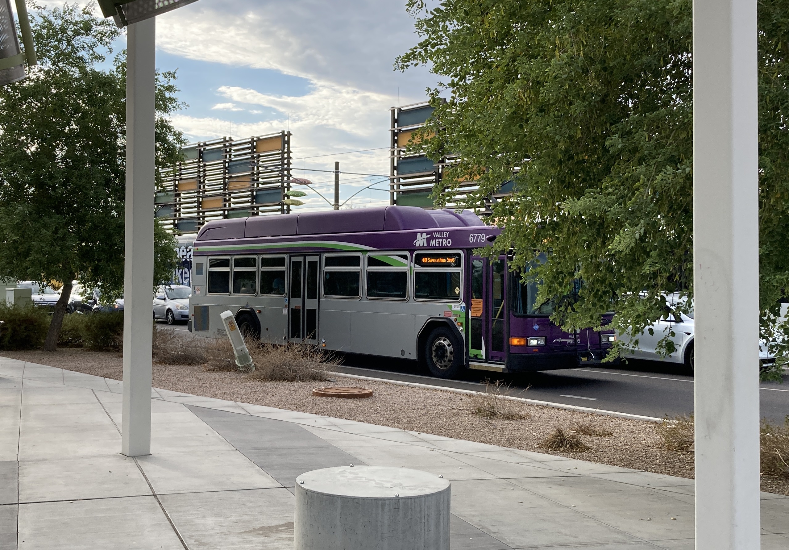 A gray and purple Valley Metro bus, with a white and green stripe, number 6779, traveling eastbound on Main Street in Mesa on route 40 to Superstition Springs Transit Center