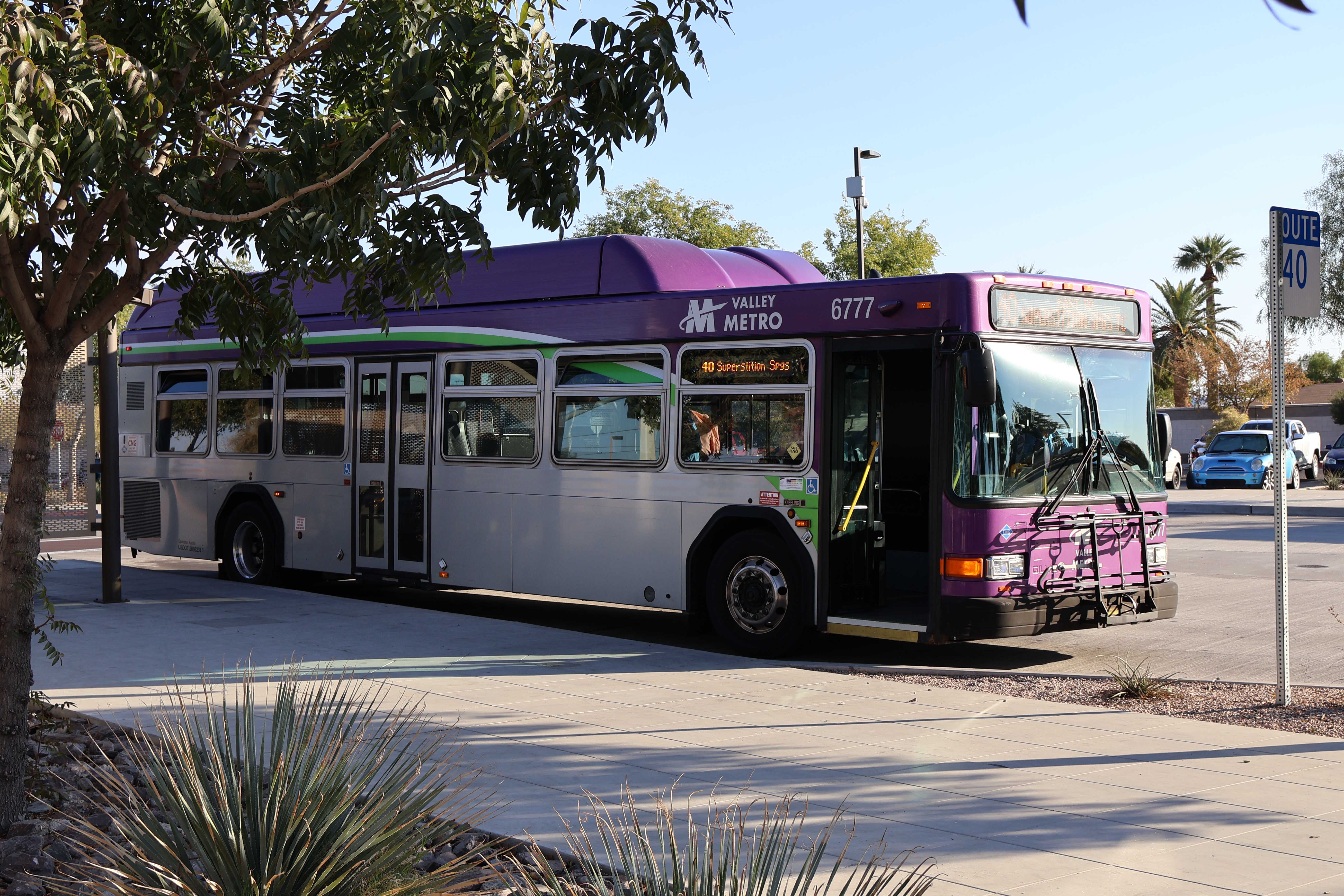 A gray and purple Valley Metro bus, with a white and green stripe, number 6777, at Gilbert Road and Main Street Park and Ride in Mesa on route 40 to Superstition Springs Transit Center