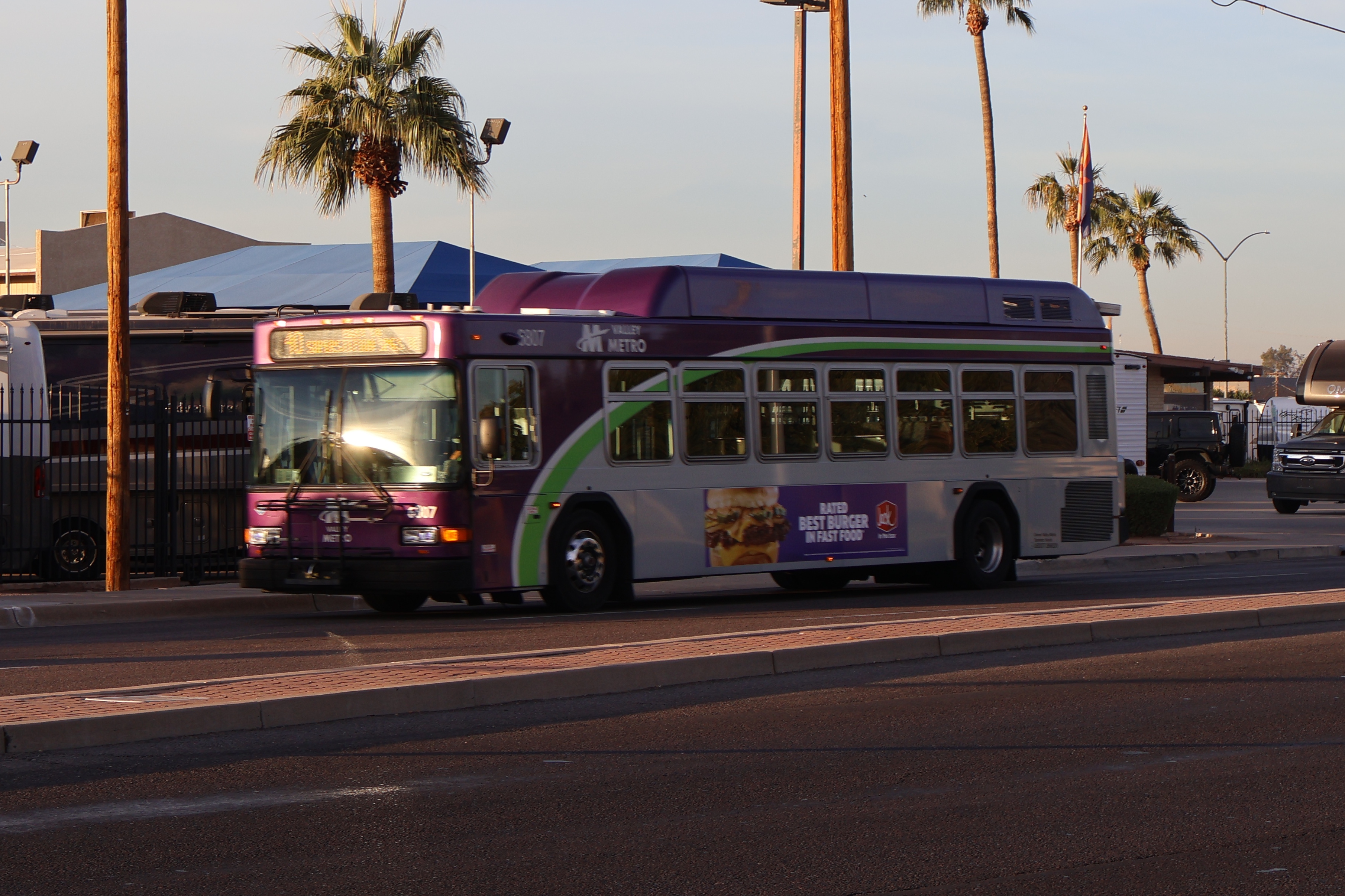 A gray and purple Valley Metro bus, with a white and green stripe, number 6807, traveling eastbound on Main Street in Mesa on route 40 to Superstition Springs Transit Center