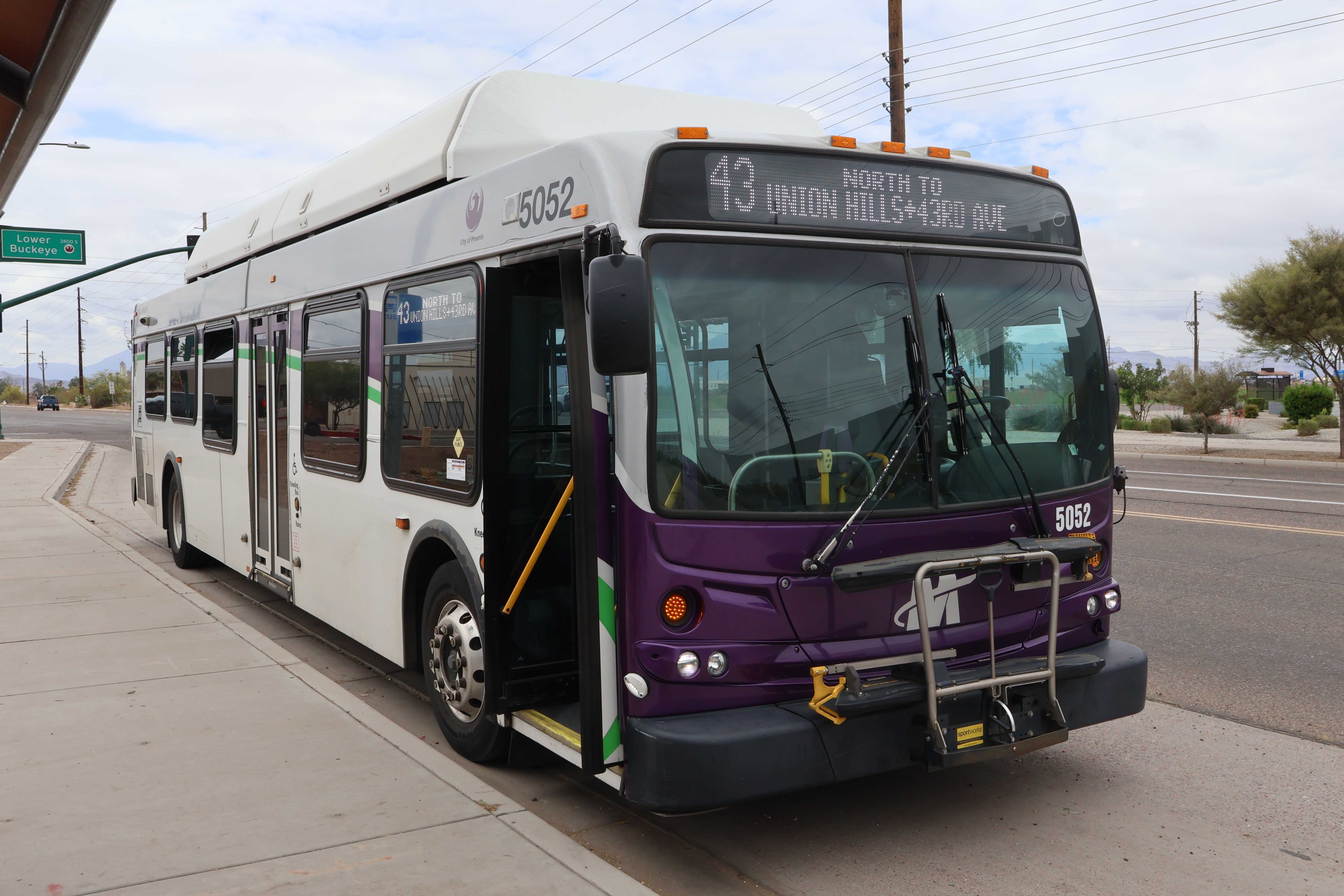A white and gray Valley Metro bus, with purple and green accent colors, number 5052, traveling northbound on 43rd Avenue in Phoenix on route 43 to 43rd Avenue and Union Hills Drive