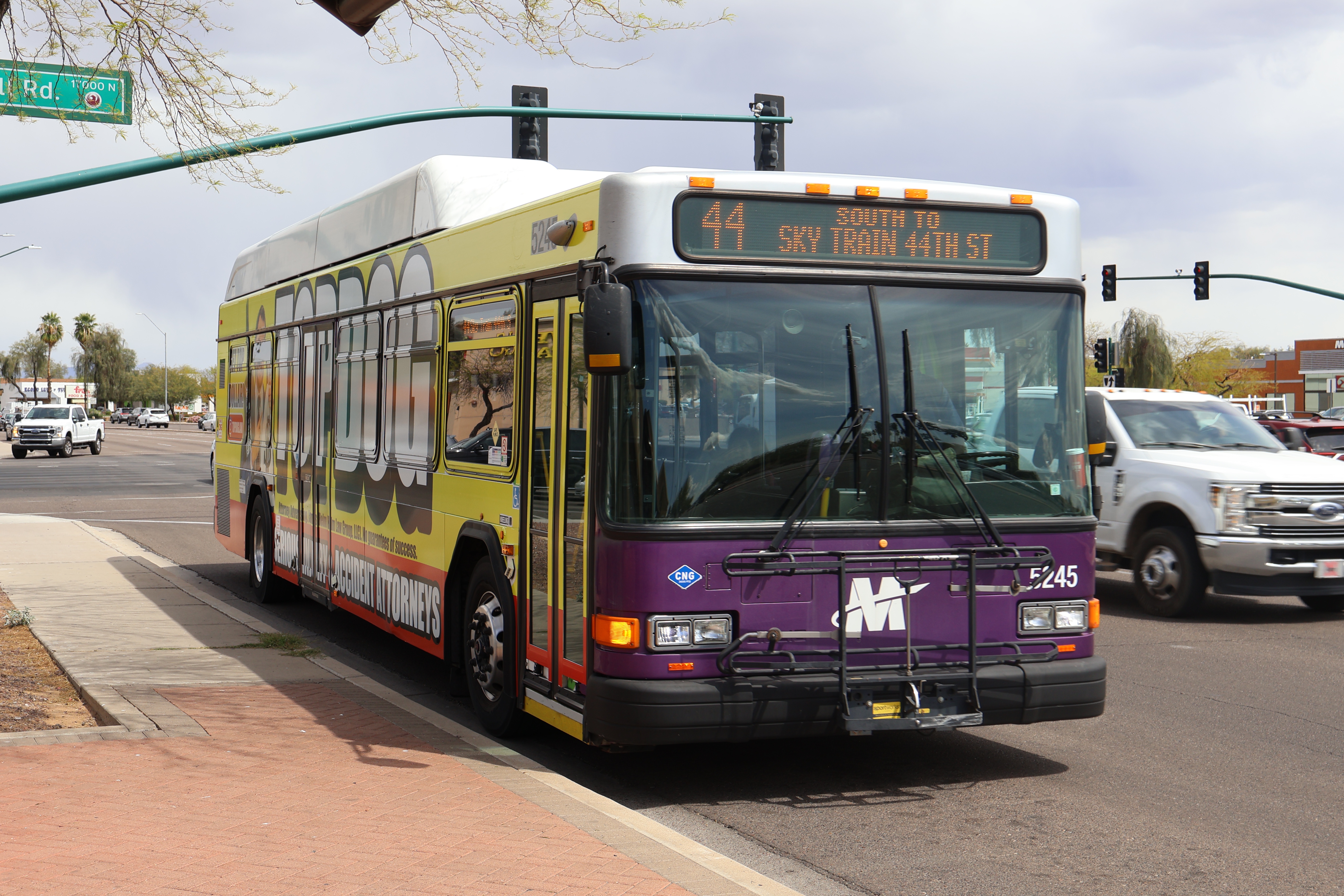 A white and gray Valley Metro bus, with purple and green accent colors, number 5245, traveling southbound on Tatum Boulevard in Phoenix on route 44 to 44th Street Sky Train Station