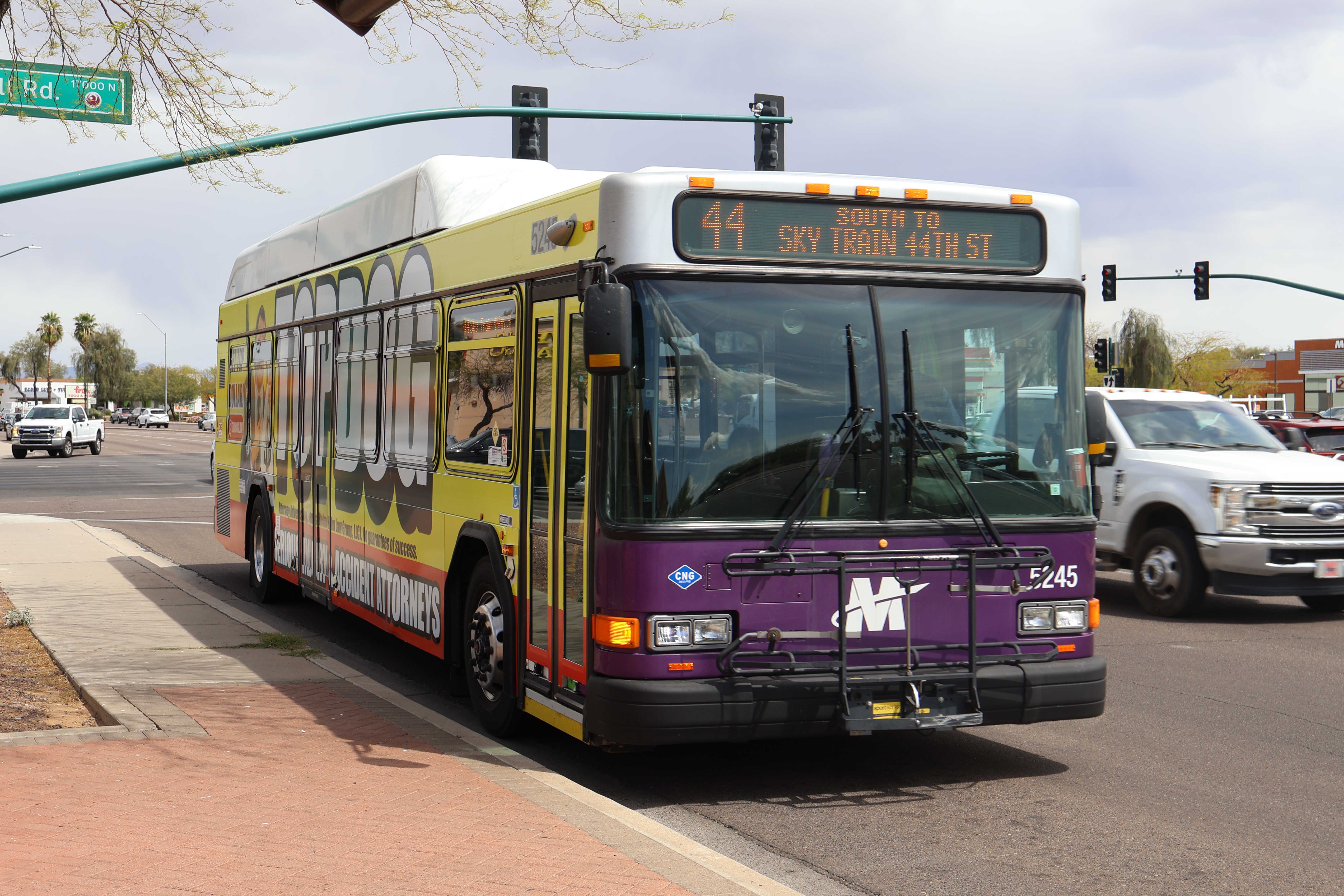 A white and gray Valley Metro bus, with purple and green accent colors, number 5245, traveling southbound on Tatum Boulevard in Phoenix on route 44 to 44th Street Sky Train Station