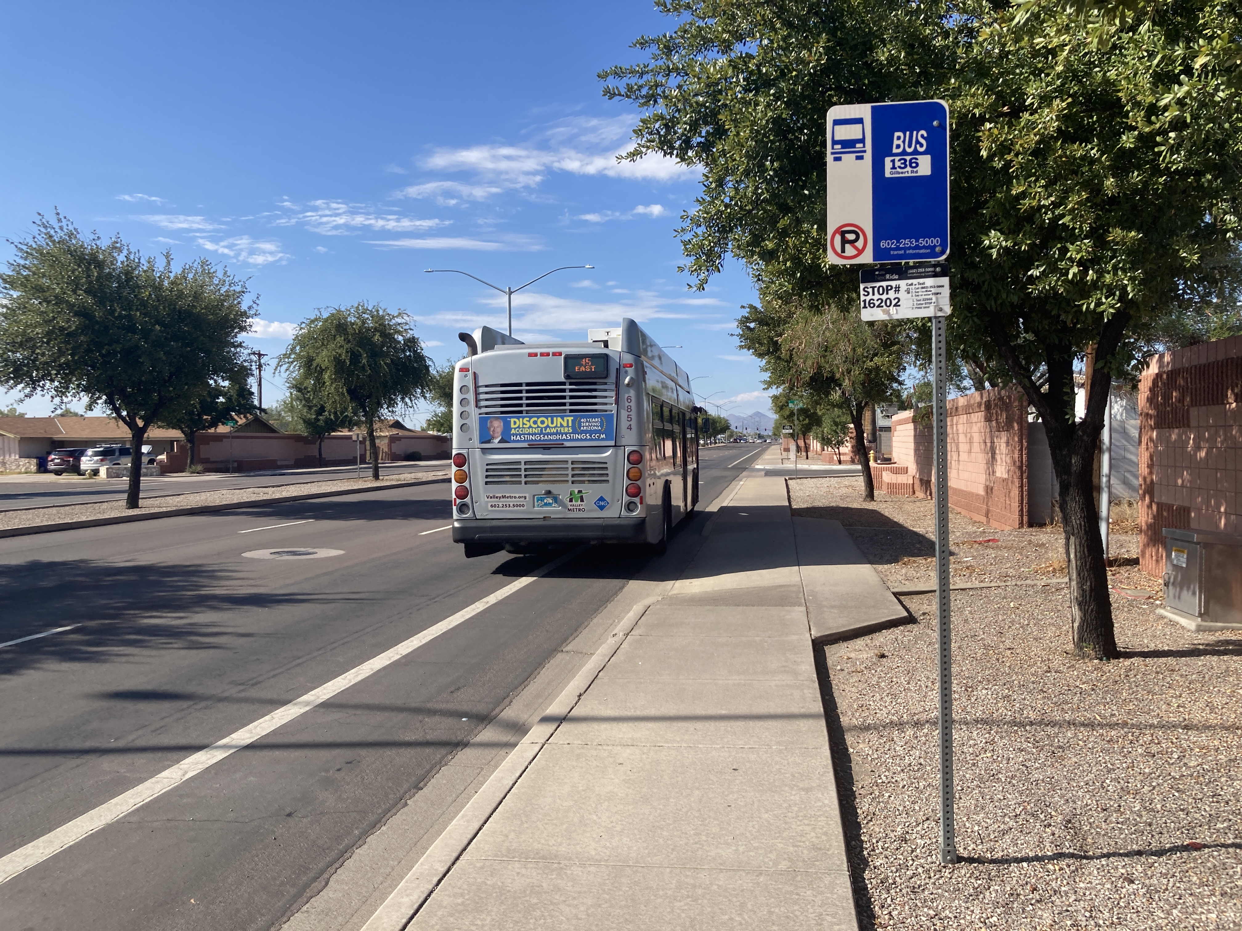 A gray and purple Valley Metro bus with a green stripe, number 6854, traveling northbound on Gilbert Road in Mesa on route 45 to Superstition Springs Transit Center