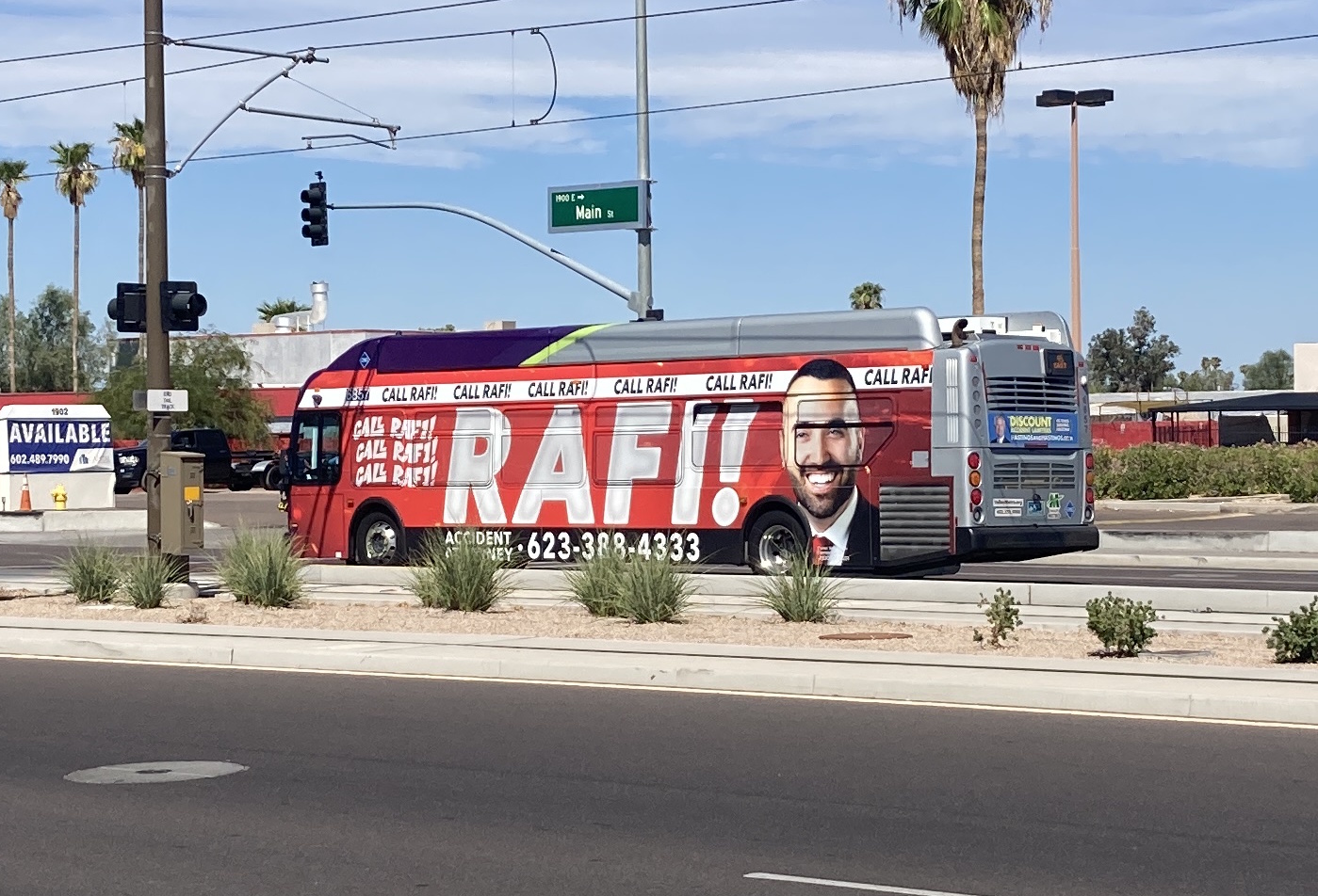 A gray and purple Valley Metro bus with a green stripe, number 6857, traveling westbound on Main Street in Mesa on route 45 to Superstition Springs Transit Center