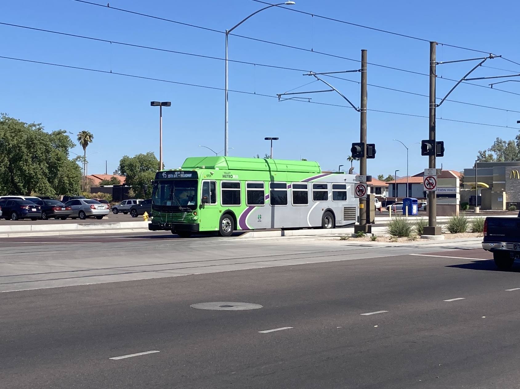 A gray and green Valley Metro bus with purple and white stripes, number 6701, traveling westbound on Main Street in Mesa on route 45 to Broadway Road and 19th Avenue