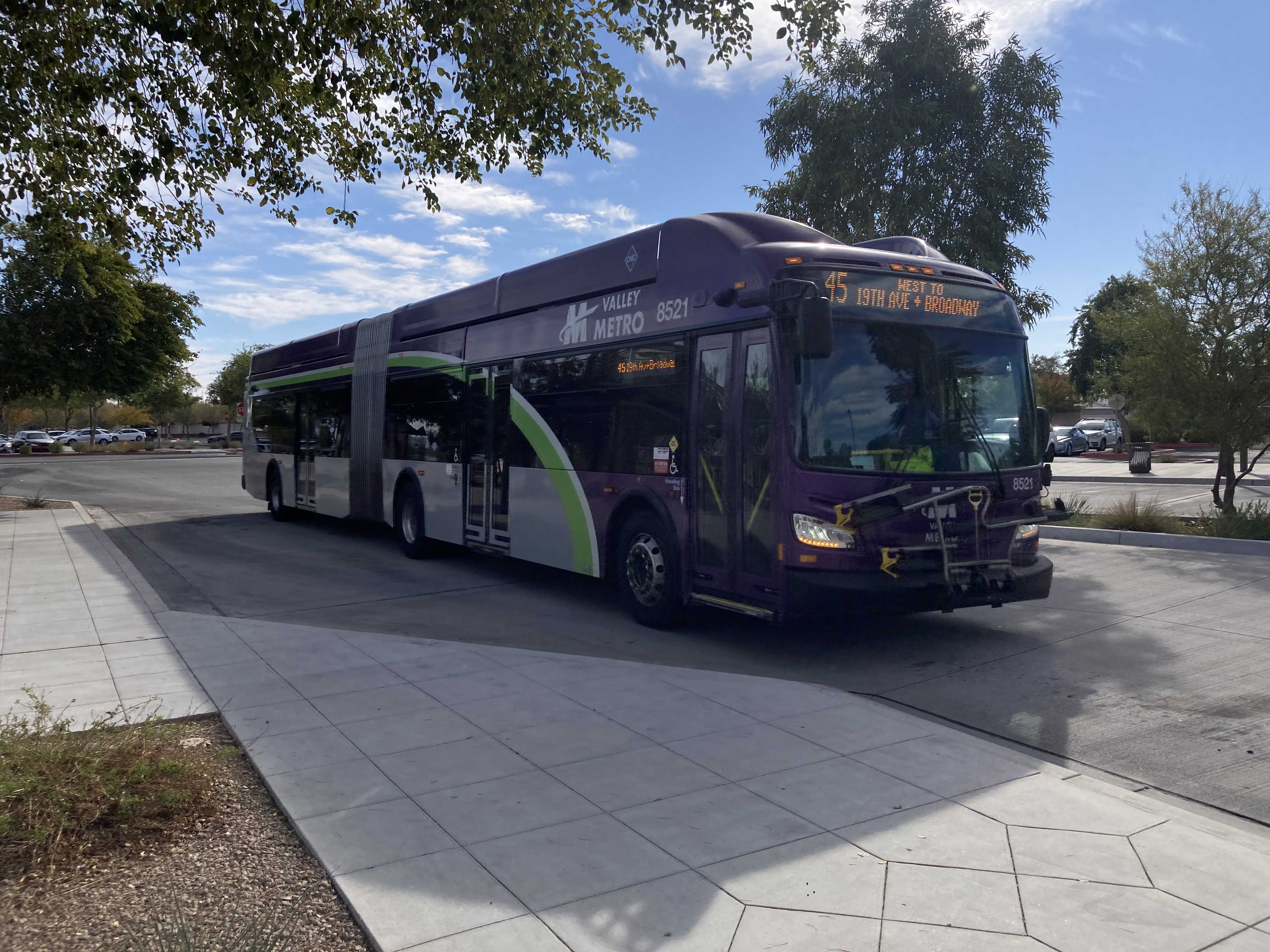 A gray and purple articulated Valley Metro bus with a green and white stripe, number 8521, at Main St/Gilbert Rd Park and Ride on route 45 to Broadway Road and 19th Avenue