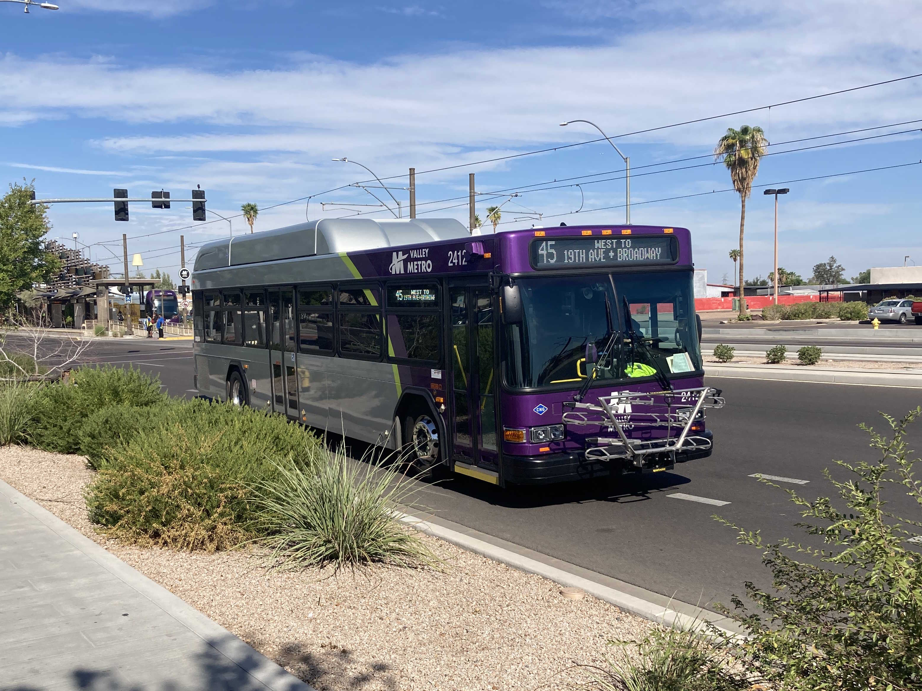 A gray and purple Valley Metro bus, with a green stripe, number 2412, traveling eastbound on Main Street in Mesa on route 45 to Broadway Road and 19th Avenue