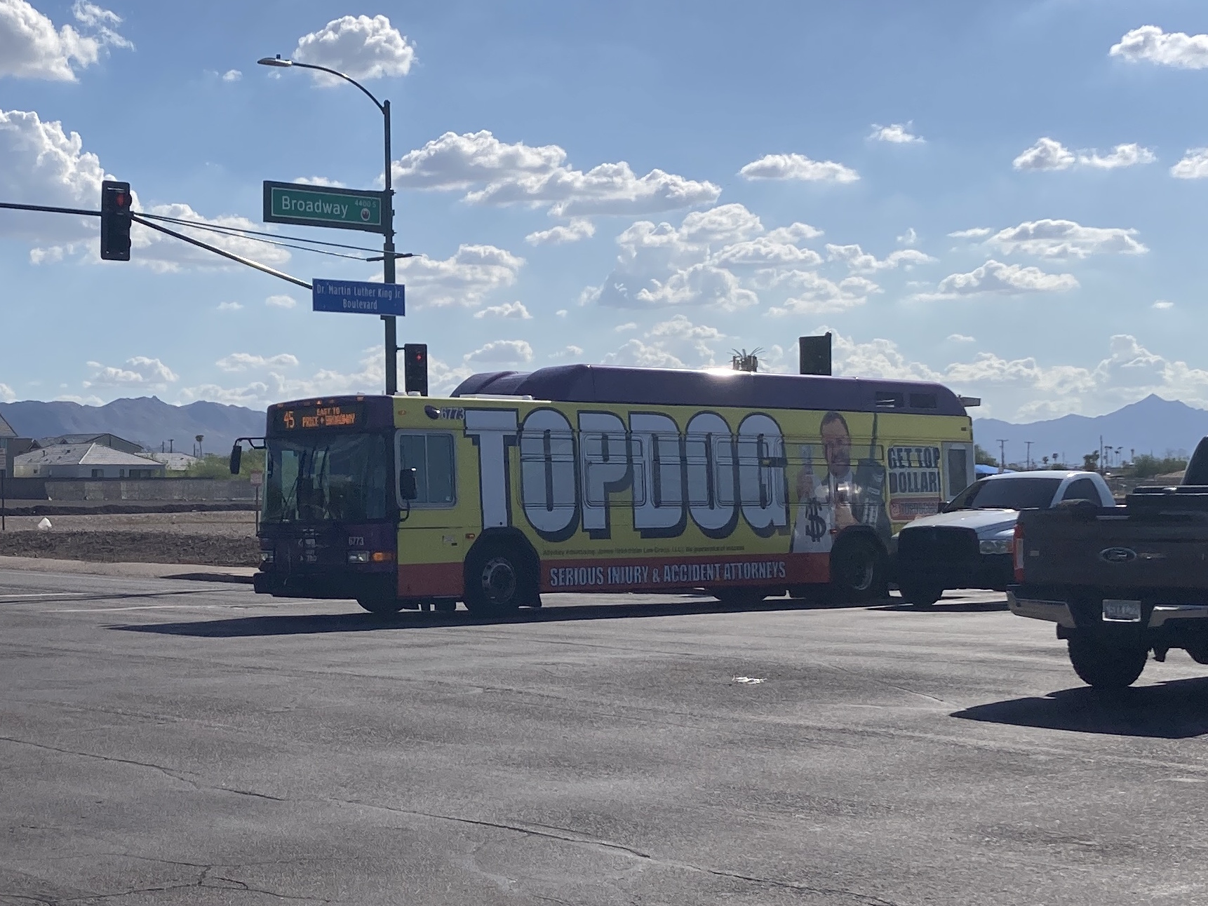 A gray and purple Valley Metro bus, with a white and green stripe, number 6773, traveling eastbound on Broadway Road in Phoenix on route 45 to Broadway Road and Price Road