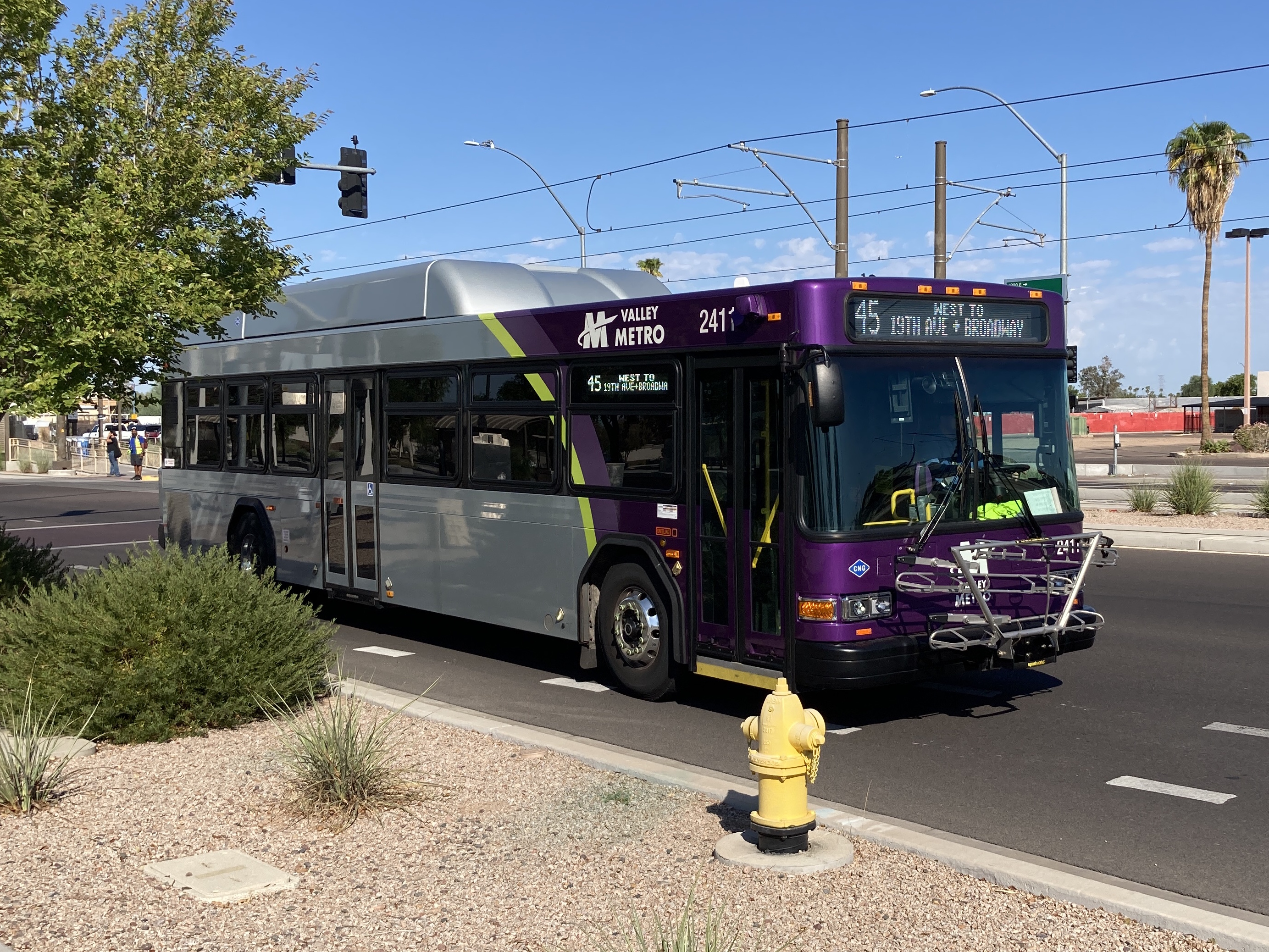 A gray and purple Valley Metro bus, with a green stripe, number 2411, traveling eastbound on Main Street in Mesa on route 45 to Broadway Road and 19th Avenue
