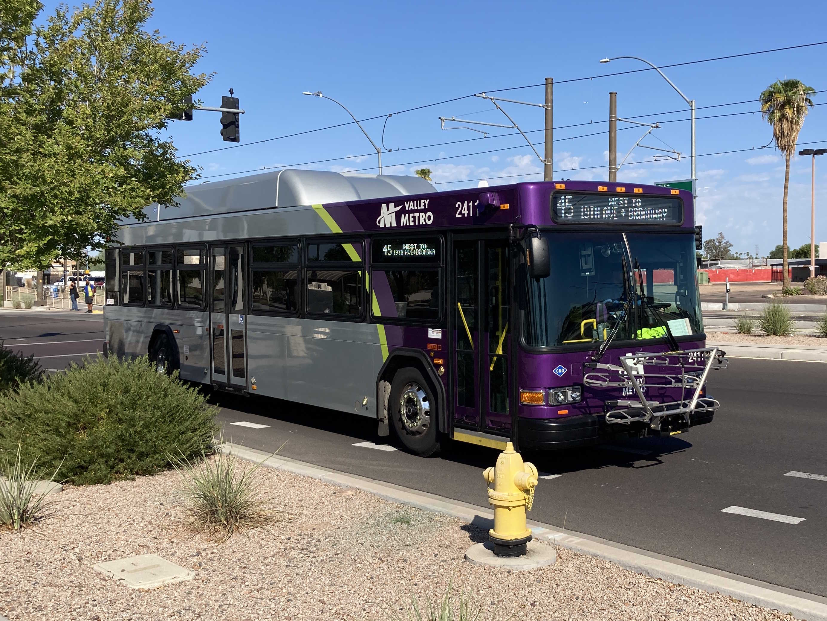 A gray and purple Valley Metro bus, with a green stripe, number 2411, traveling eastbound on Main Street in Mesa on route 45 to Broadway Road and 19th Avenue