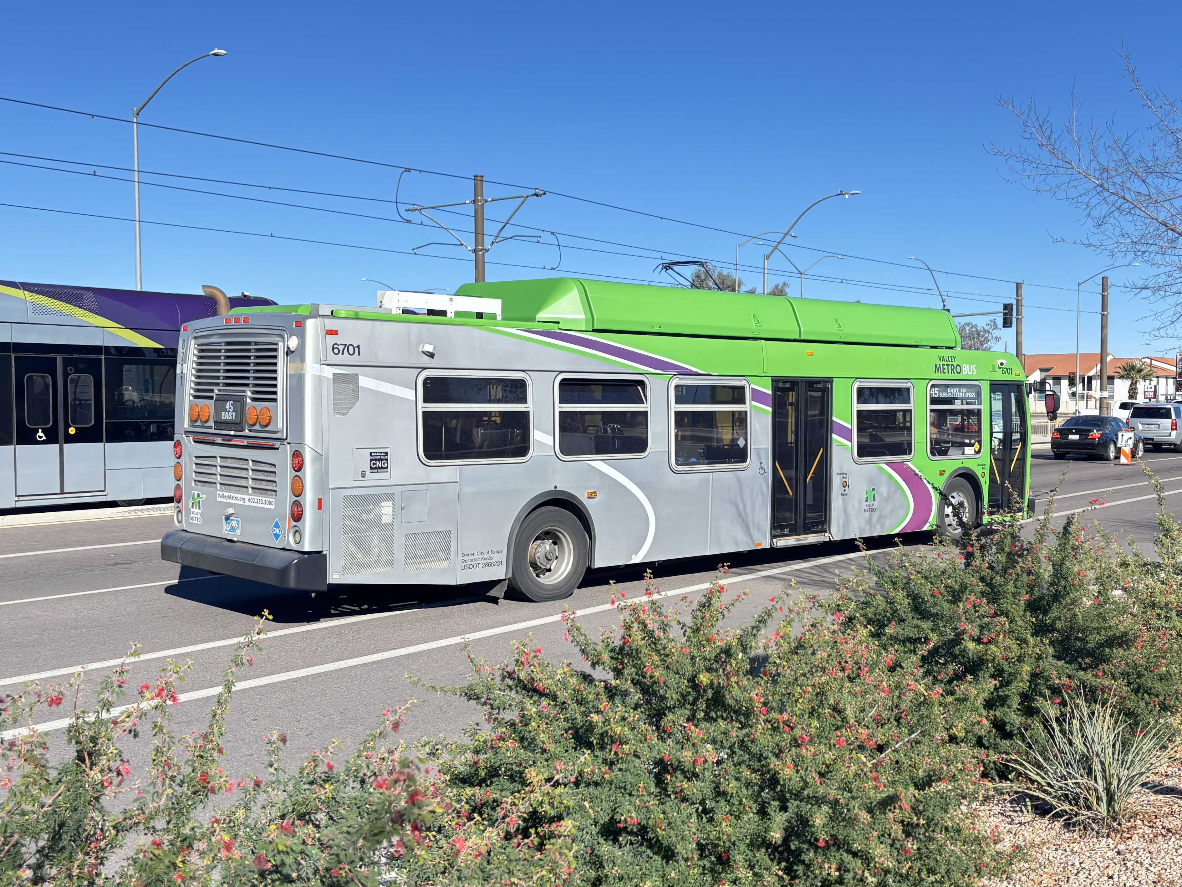 A gray and green Valley Metro bus, number 6701, traveling eastbound on Main Street in Mesa on route 45 to Superstition Springs Transit Center