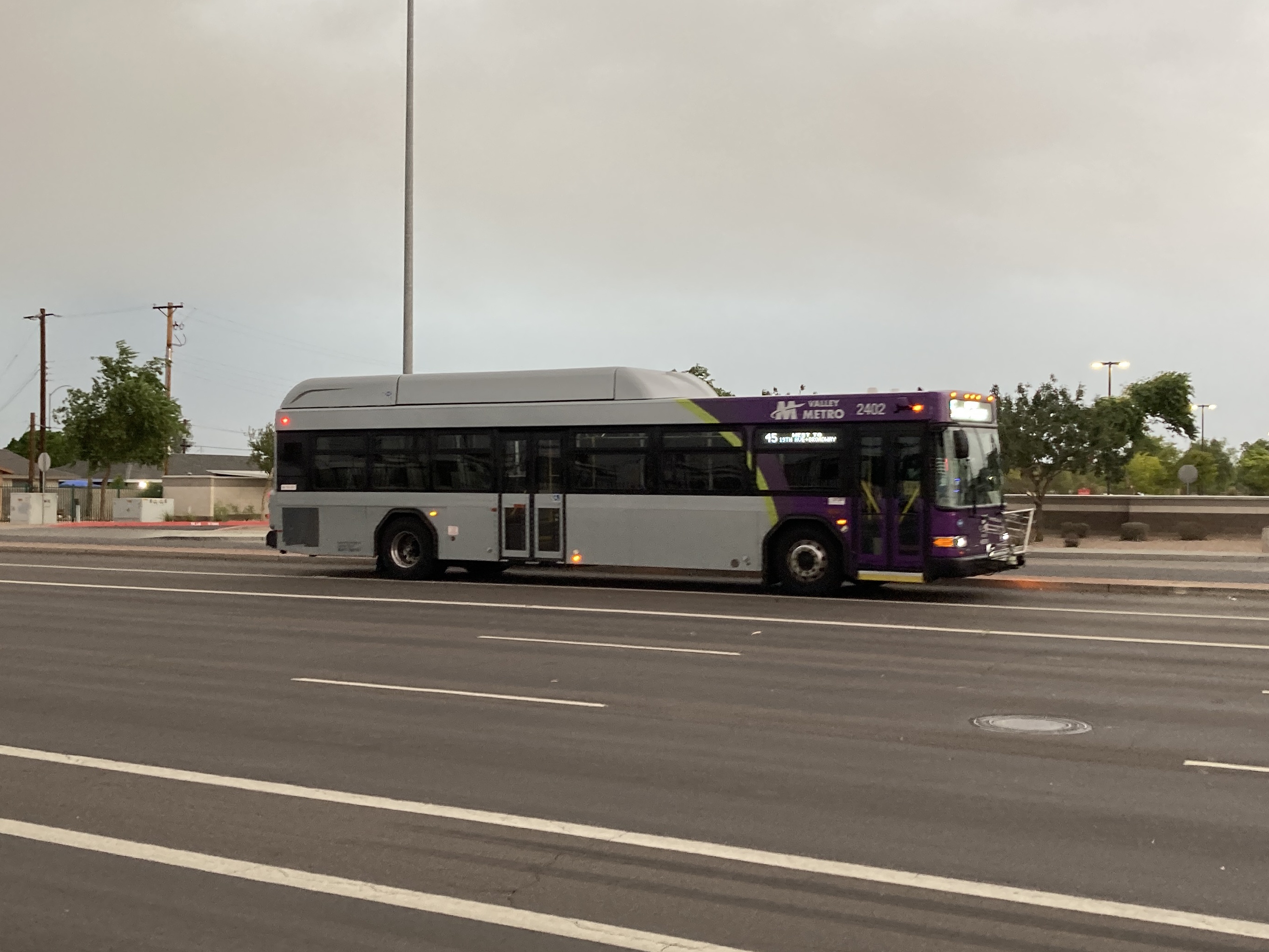 A gray and purple Valley Metro bus, with a green stripe, number 2402, traveling northbound on Gilbert Road in Mesa on route 45 to Broadway Road and 19th Avenue