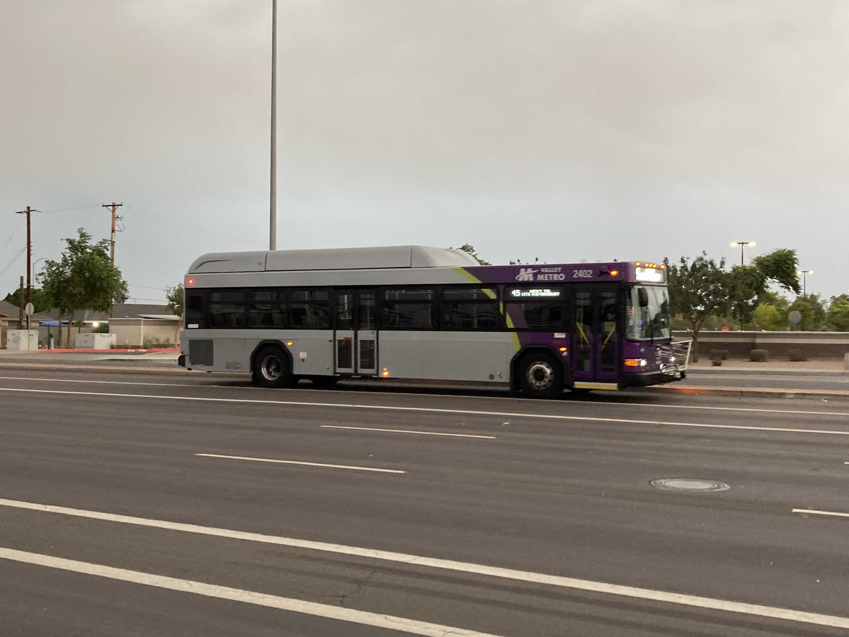 A gray and purple Valley Metro bus, with a green stripe, number 2402, traveling northbound on Gilbert Road in Mesa on route 45 to Broadway Road and 19th Avenue