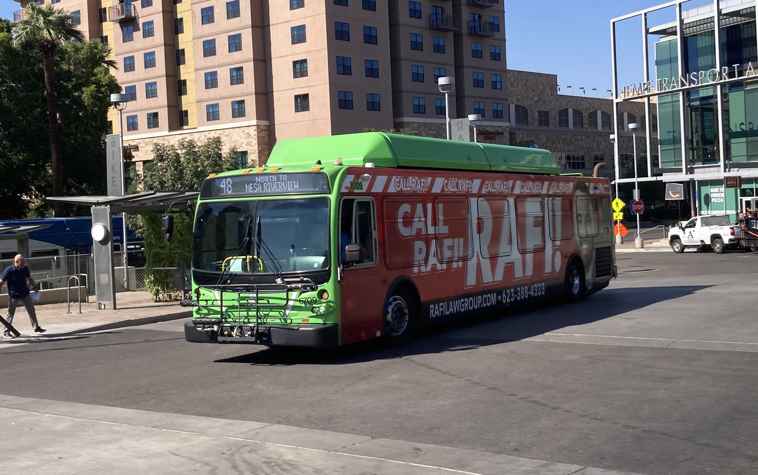 A gray and green Valley Metro bus, with a purple and white stripe, number 6709, at the Tempe Transportation Center, traveling route 48 to Mesa Riverview