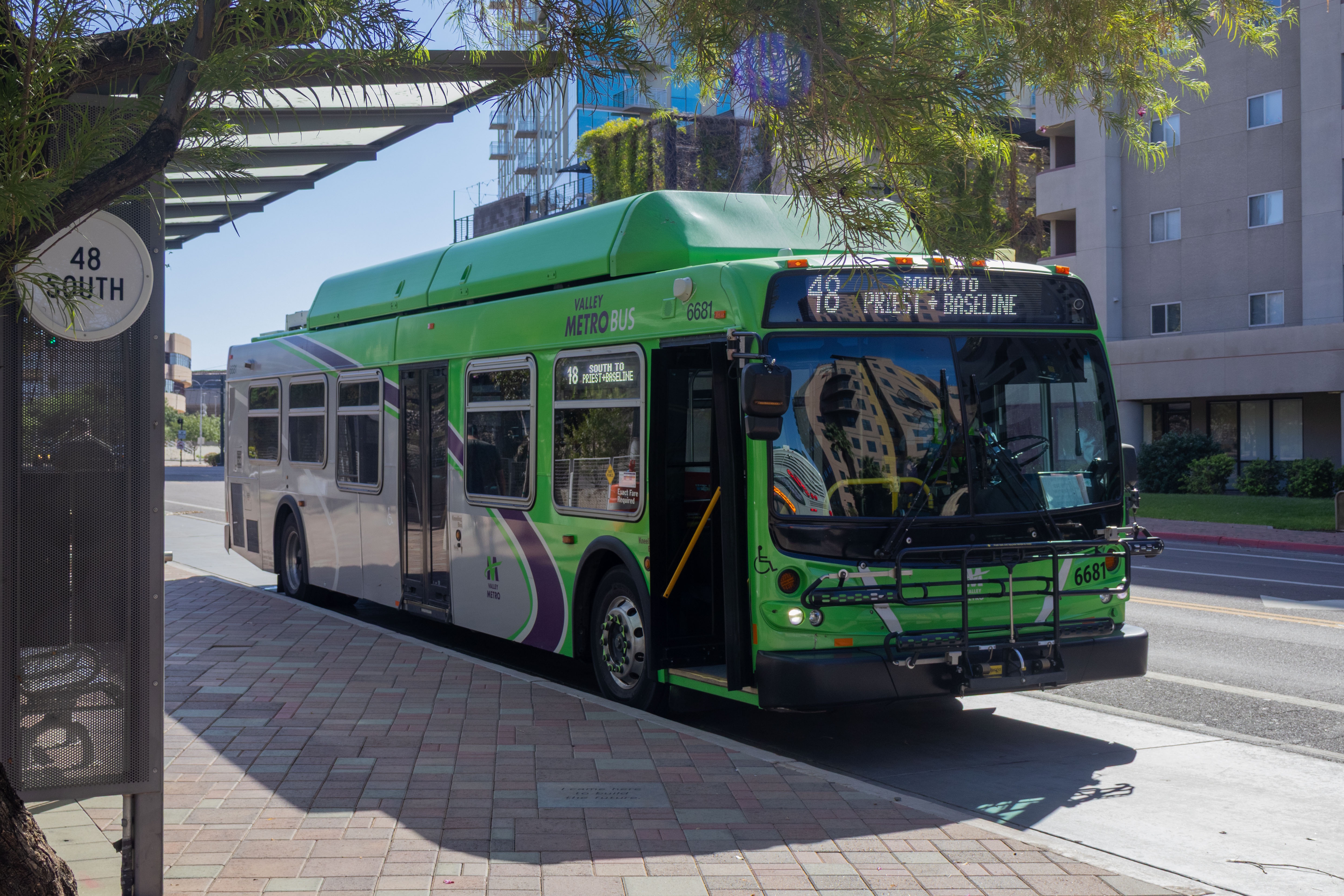 A gray and green Valley Metro bus, with a purple and white stripe, number 6681, at the Tempe Transportation Center, traveling route 48 to Baseline Road and Priest Drive