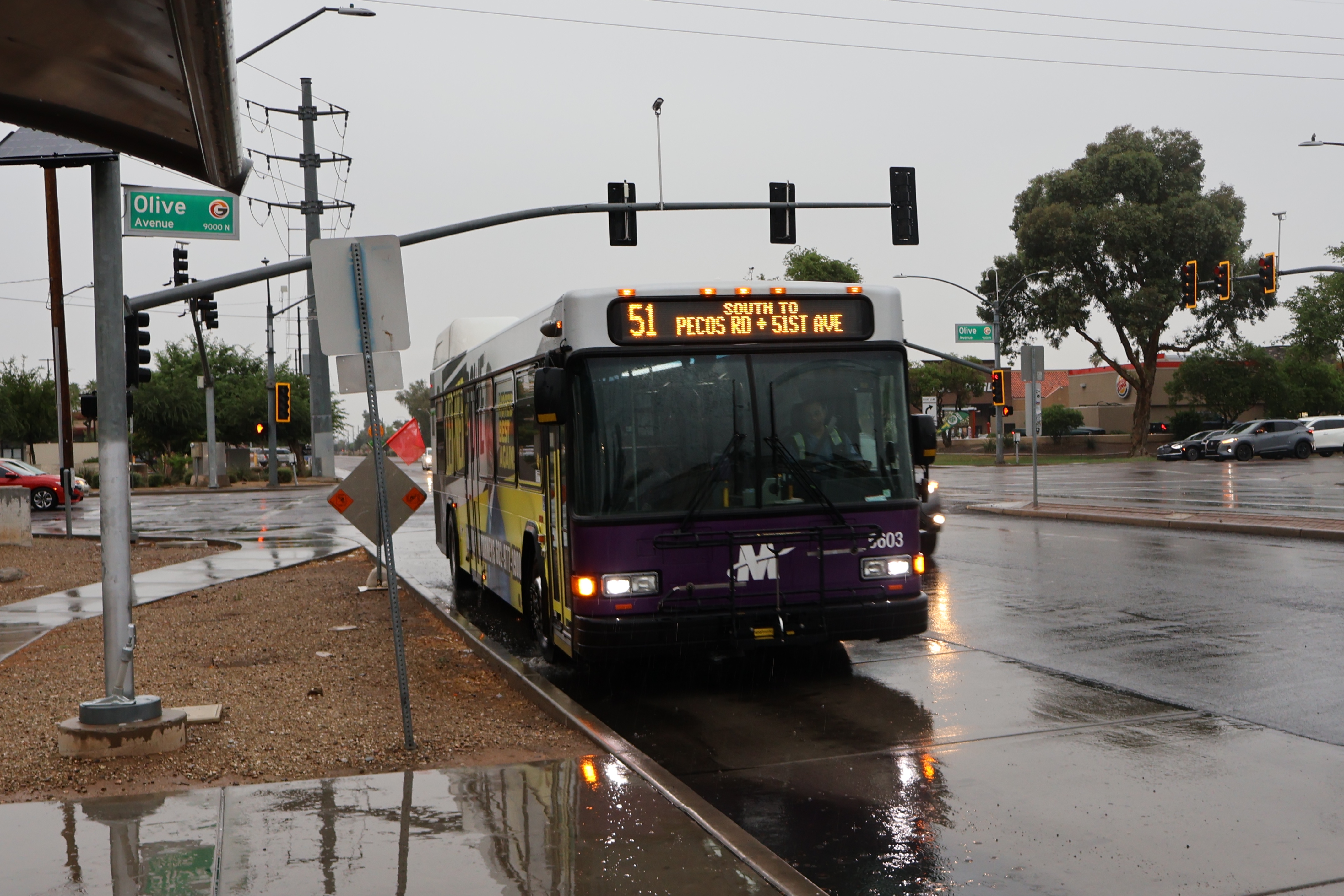 A white and gray Valley Metro bus, with purple and green accent colors, number 5603, traveling southbound on 51st Avenue in Glendale on route 51 to 51st Avenue and Pecos Road