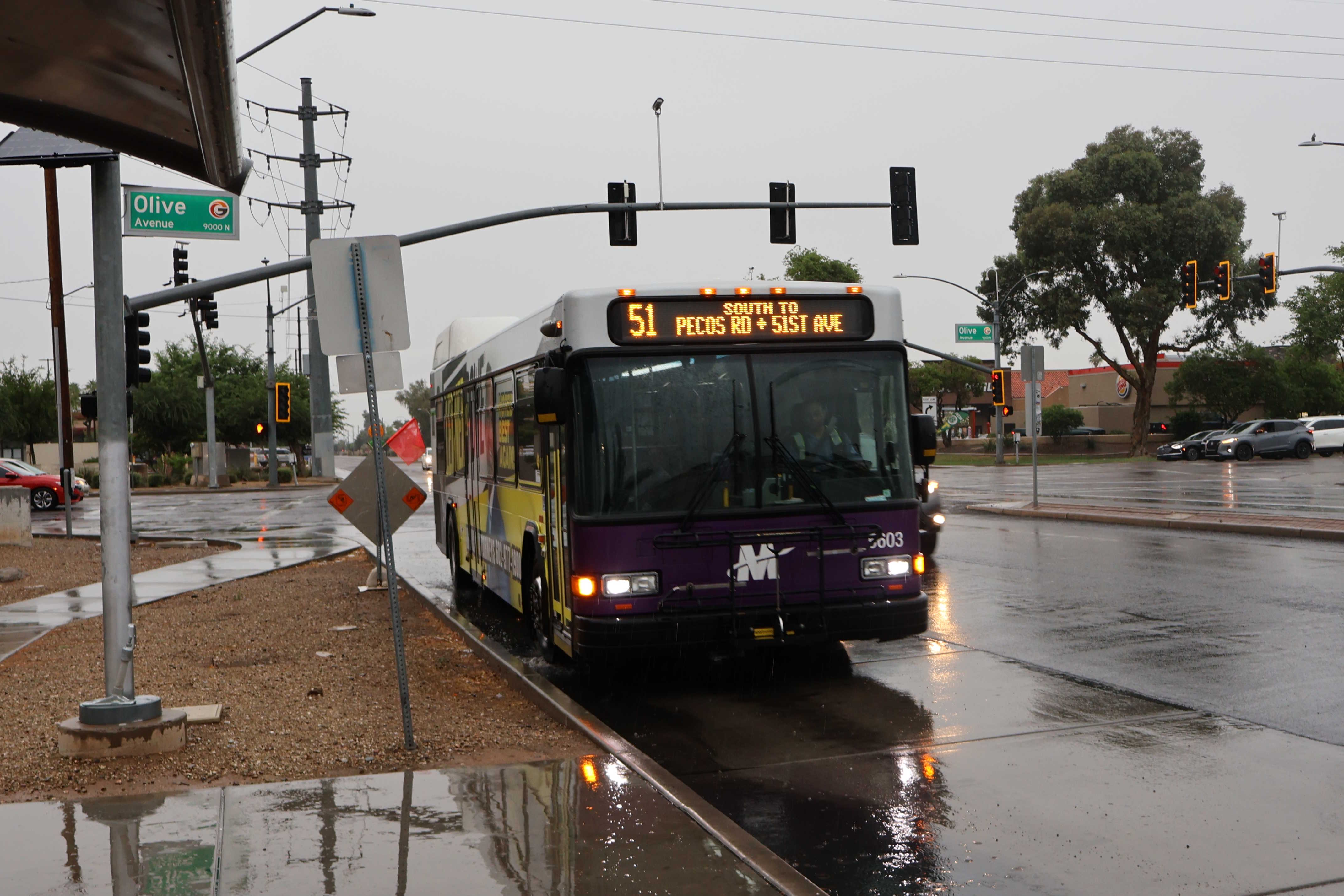 A white and gray Valley Metro bus, with purple and green accent colors, number 5603, traveling southbound on 51st Avenue in Glendale on route 51 to 51st Avenue and Pecos Road