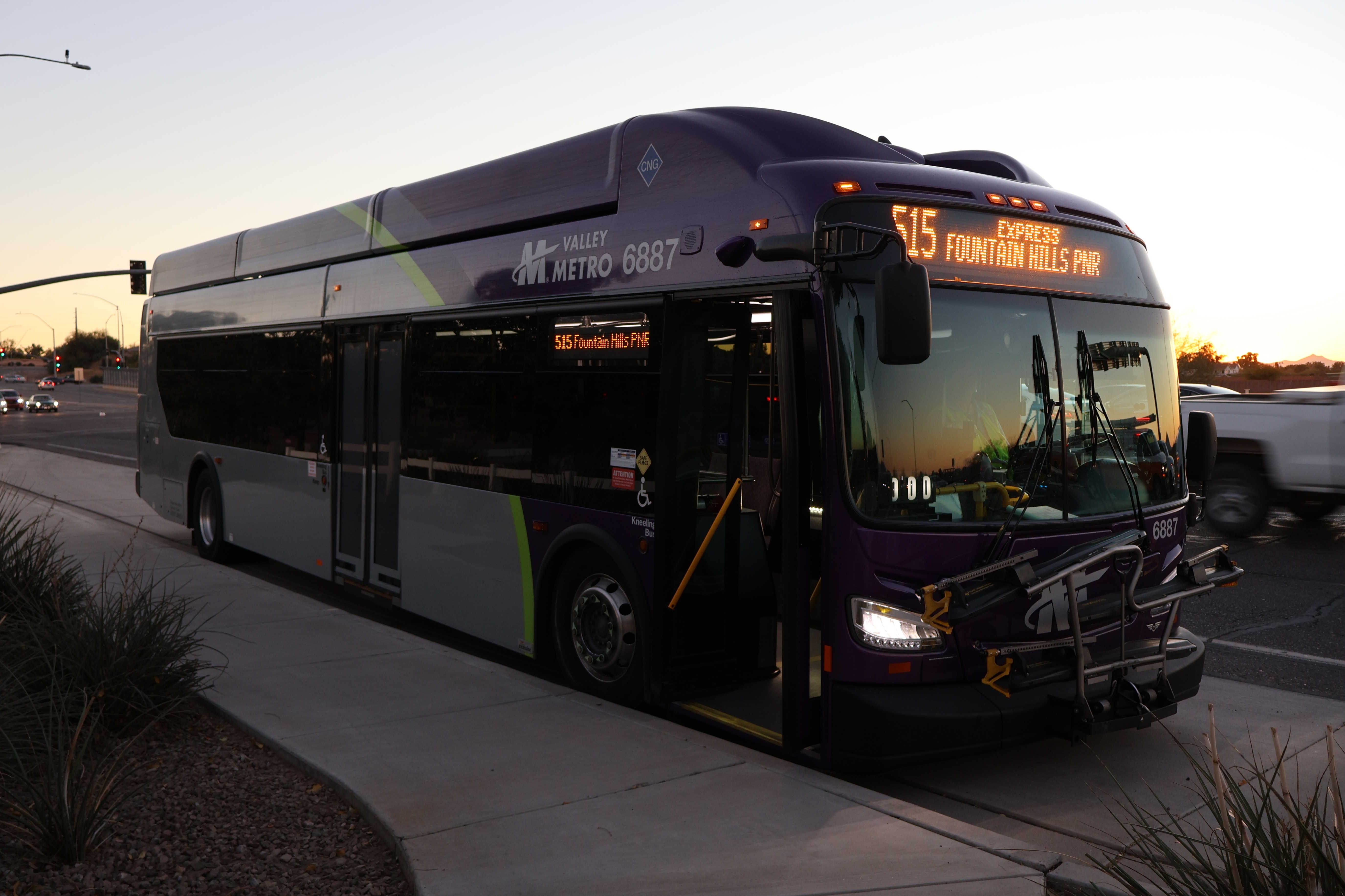 A gray and purple Valley Metro bus, with a green stripe, number 6887, traveling northbound on Gilbert Road in Mesa on route 515 to Fountain Hills Library