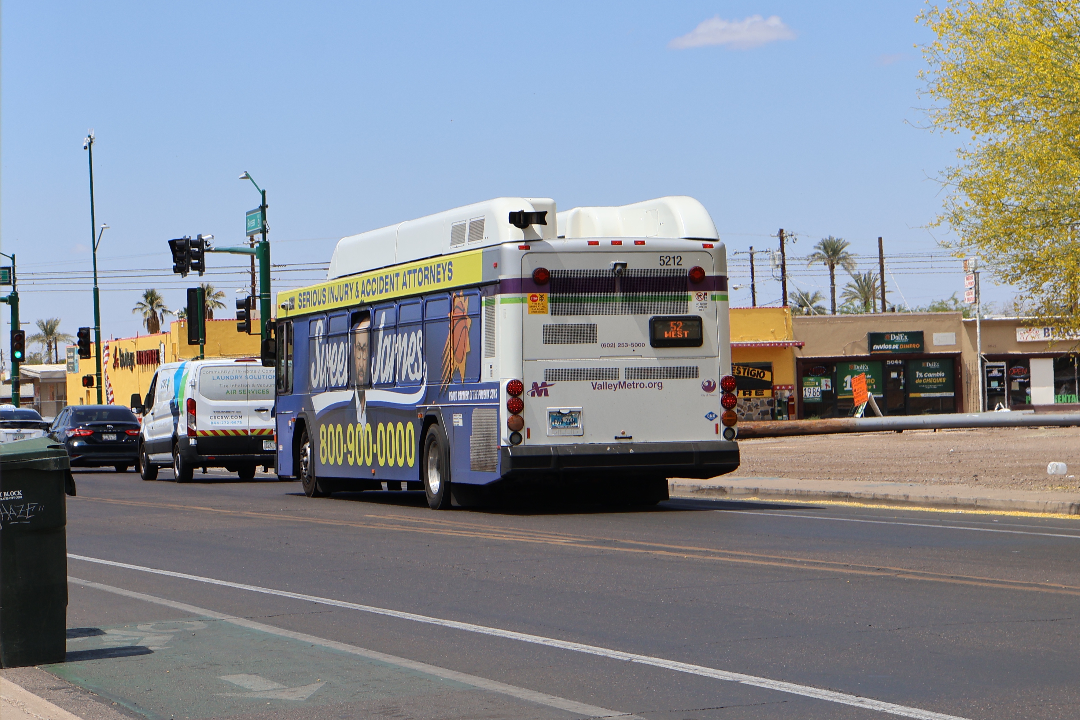 A white and gray Valley Metro bus, with purple and green accent colors, number 5212, traveling westbound on Roeser Road in Phoenix on route 52 to Roeser Road and 19th Avenue