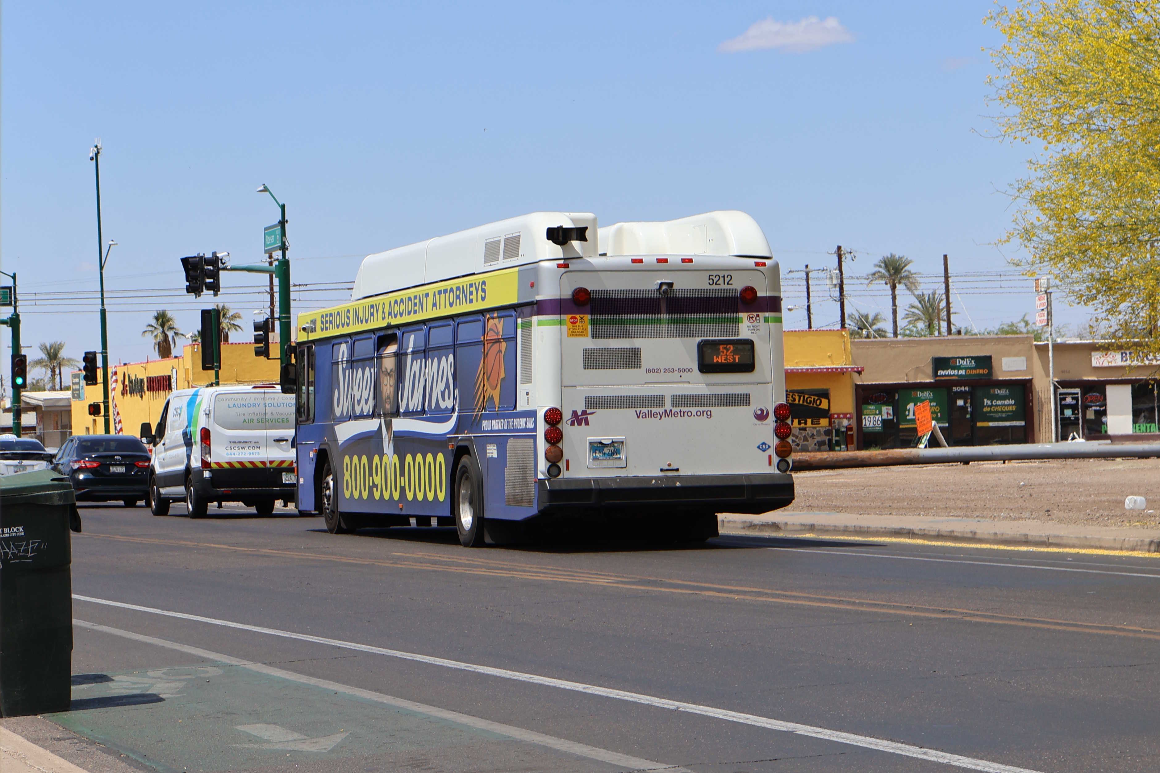 A white and gray Valley Metro bus, with purple and green accent colors, number 5212, traveling westbound on Roeser Road in Phoenix on route 52 to Roeser Road and 19th Avenue