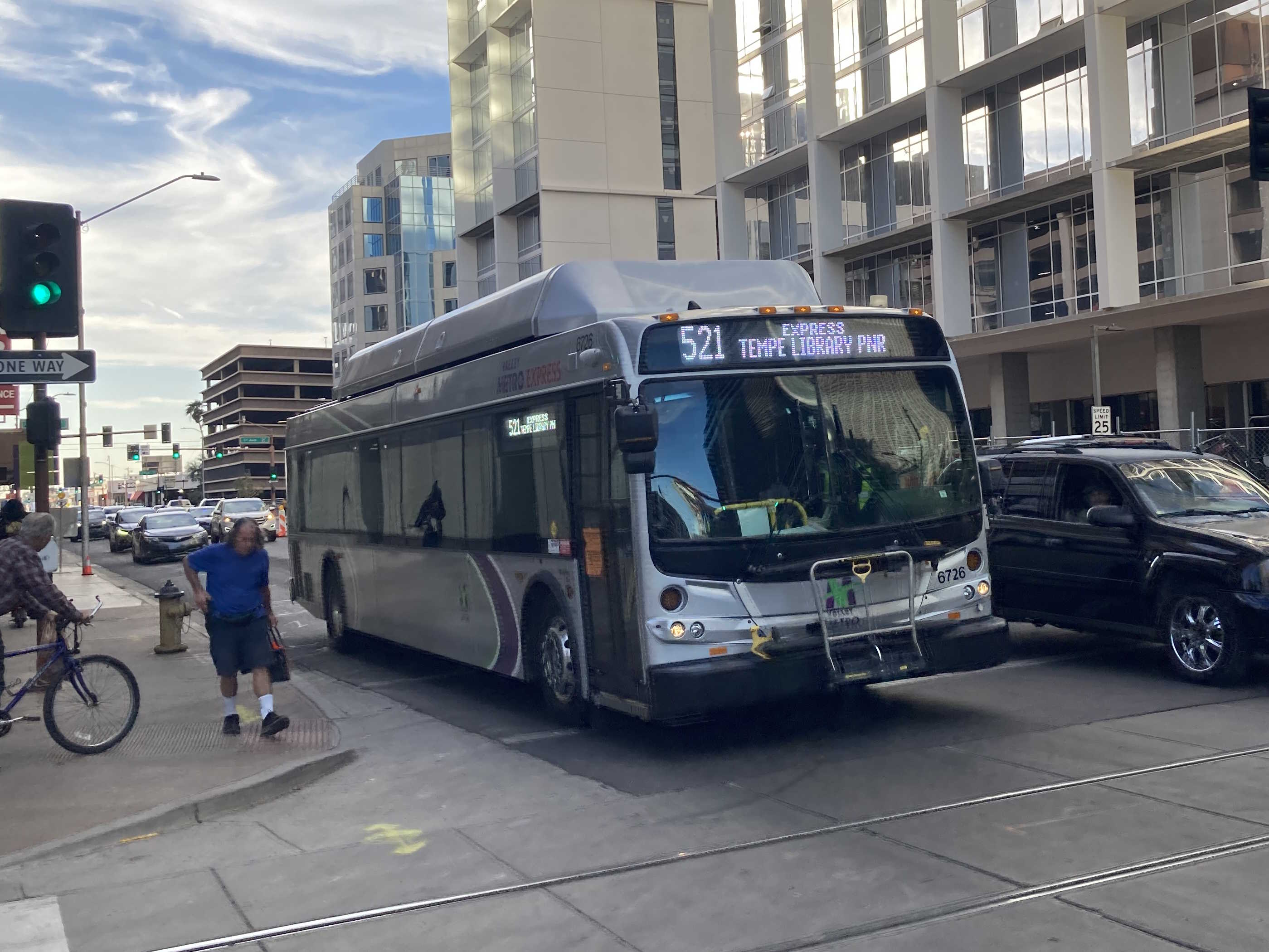 A silver Valley Metro bus, with green, purple, and white stripes, number 6726, traveling eastbound on Van Buren Street in Phoenix on route 521 to Tempe Library Park and Ride