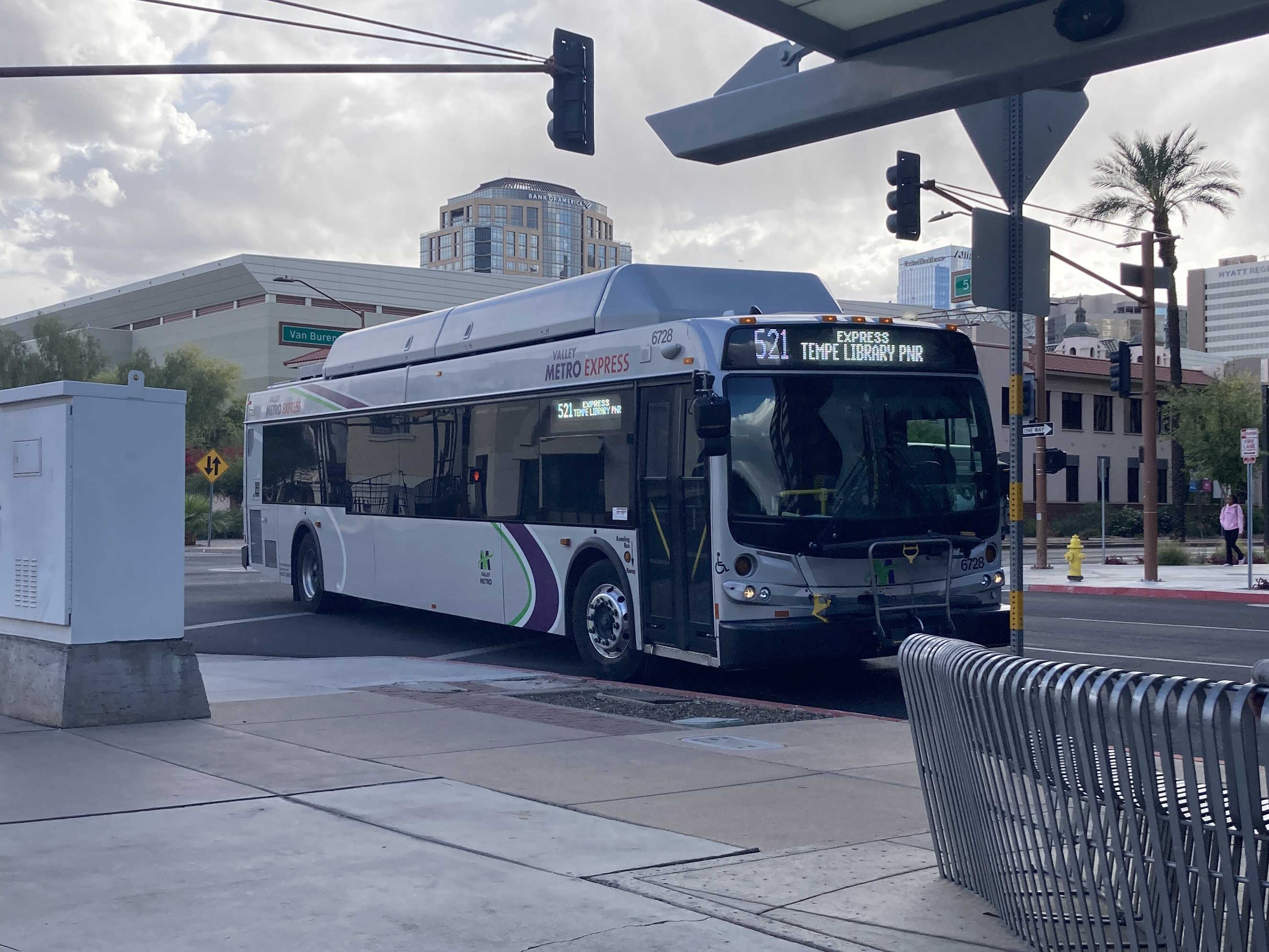 A silver Valley Metro bus, with green, purple, and white stripes, number 6728, traveling northbound on 5th Street in Phoenix on route 521 to Tempe Library Park and Ride
