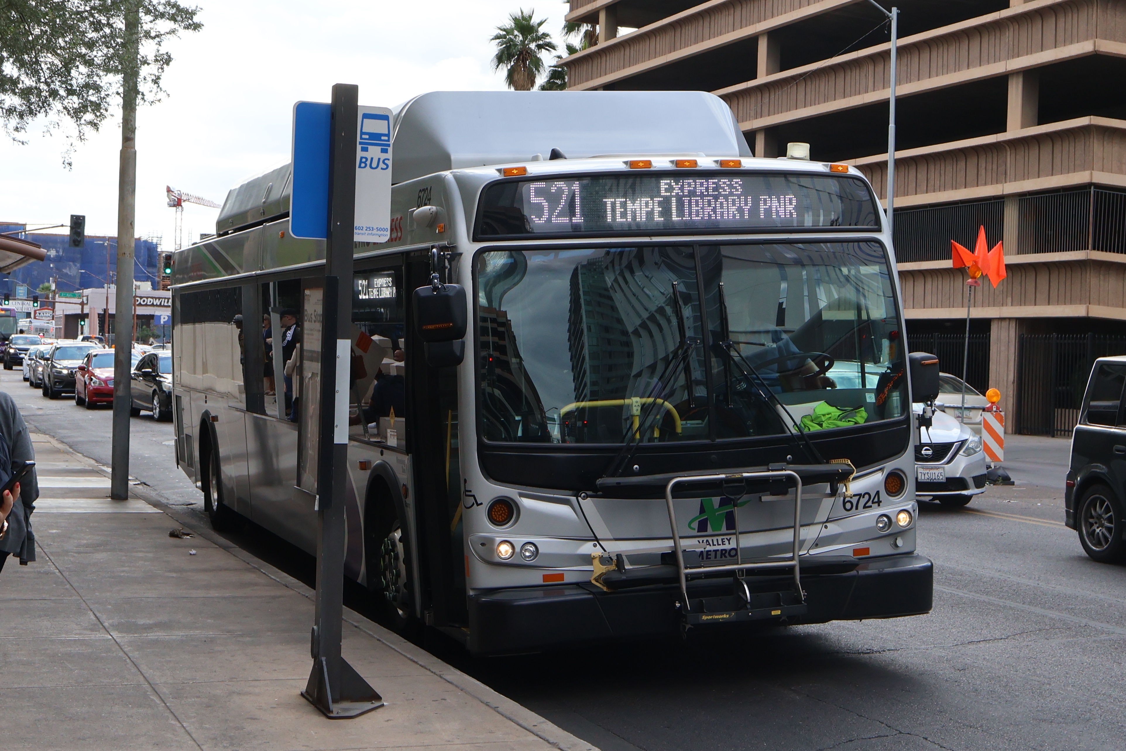 A silver Valley Metro bus, with green, purple, and white stripes, number 6724, traveling eastbound on Van Buren Street in Phoenix on route 521 to Tempe Library Park and Ride
