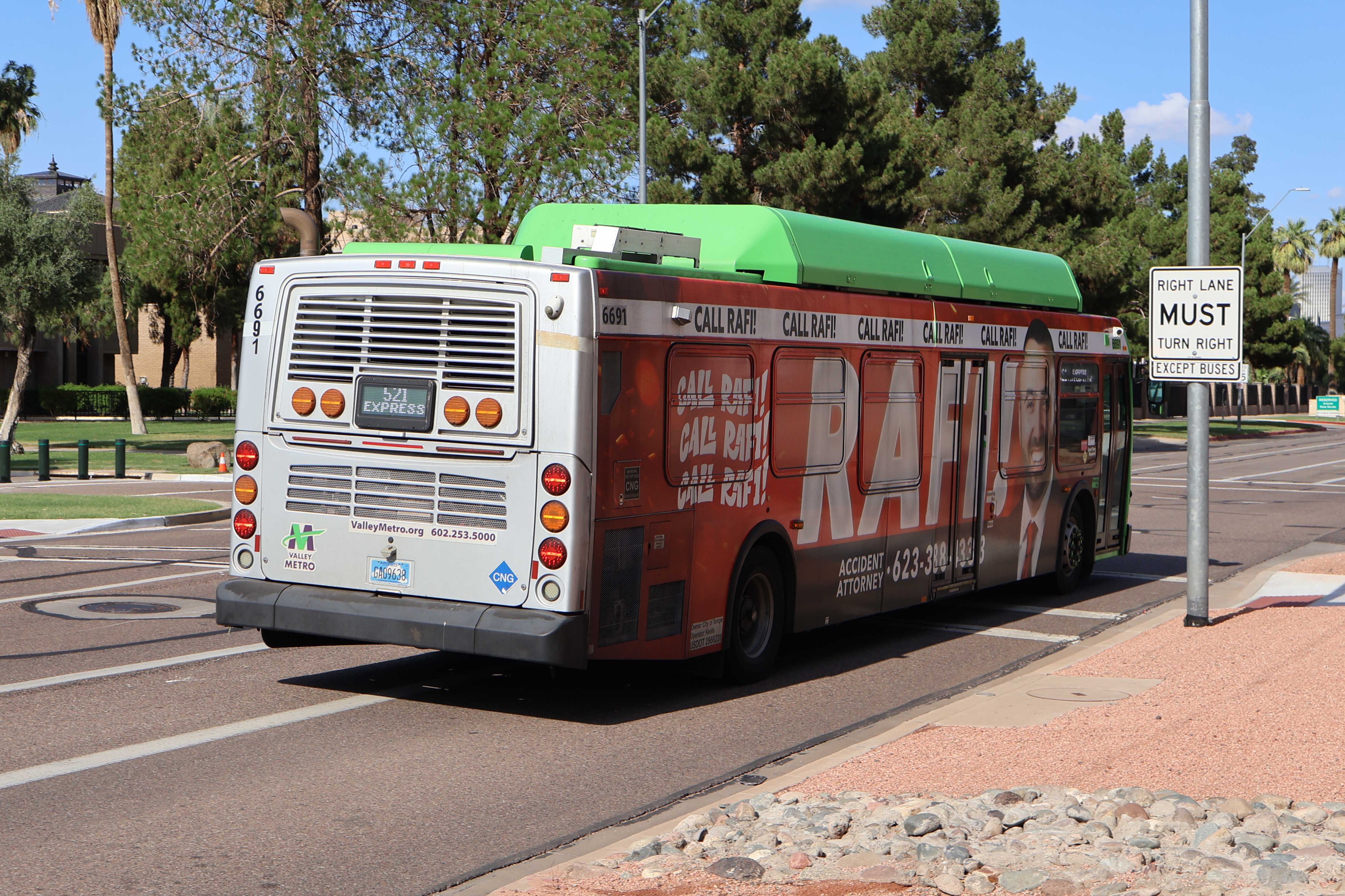 A green and gray Valley Metro bus, with a purple stripe, number 6691, traveling eastbound on Jefferson Street in Phoenix on route 521 to Tempe Library Park and Ride