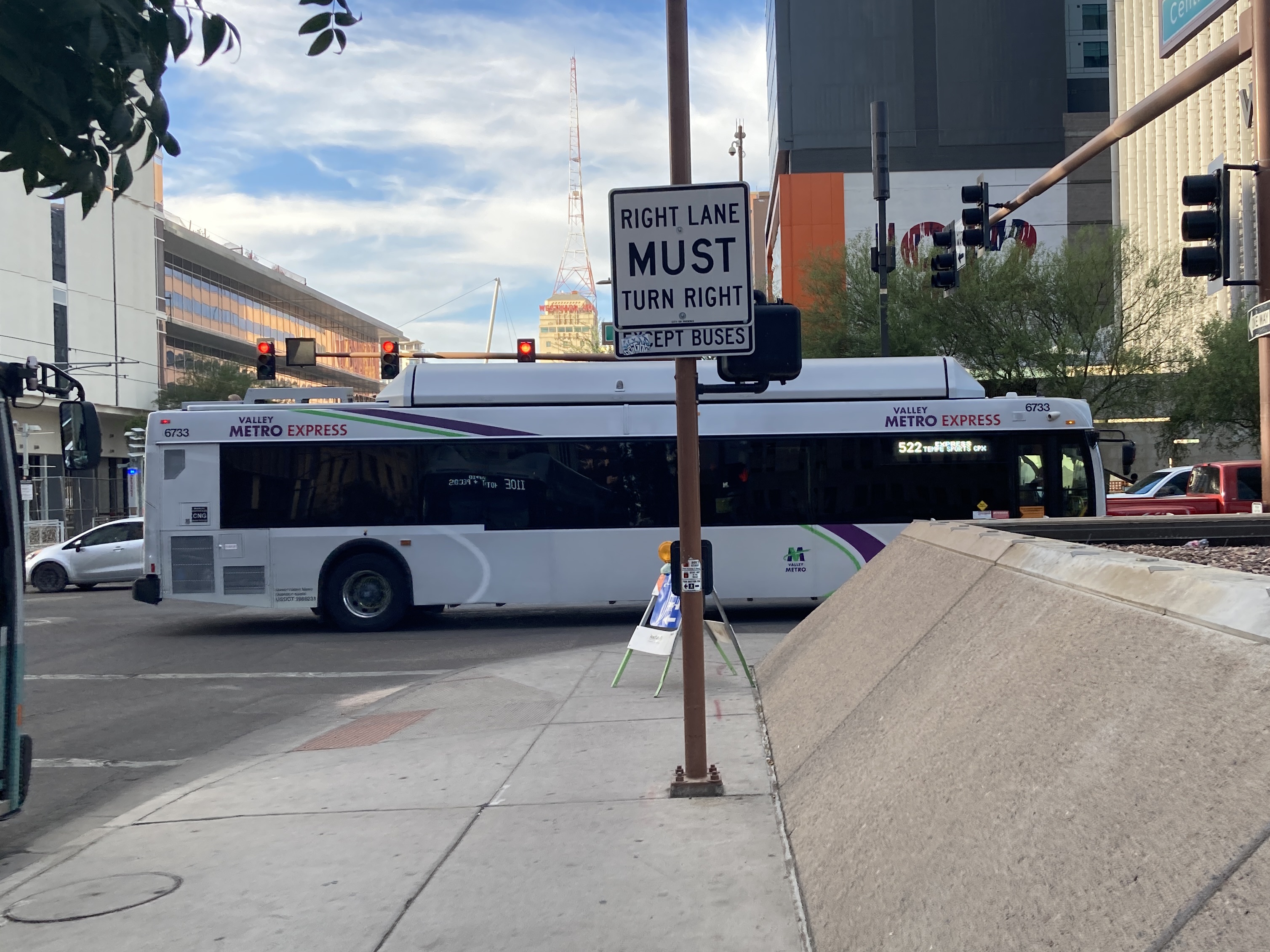 A silver Valley Metro bus, with green, purple, and white stripes, number 6733, traveling eastbound on Van Buren Street in Phoenix on route 522 to Tempe Sports Complex