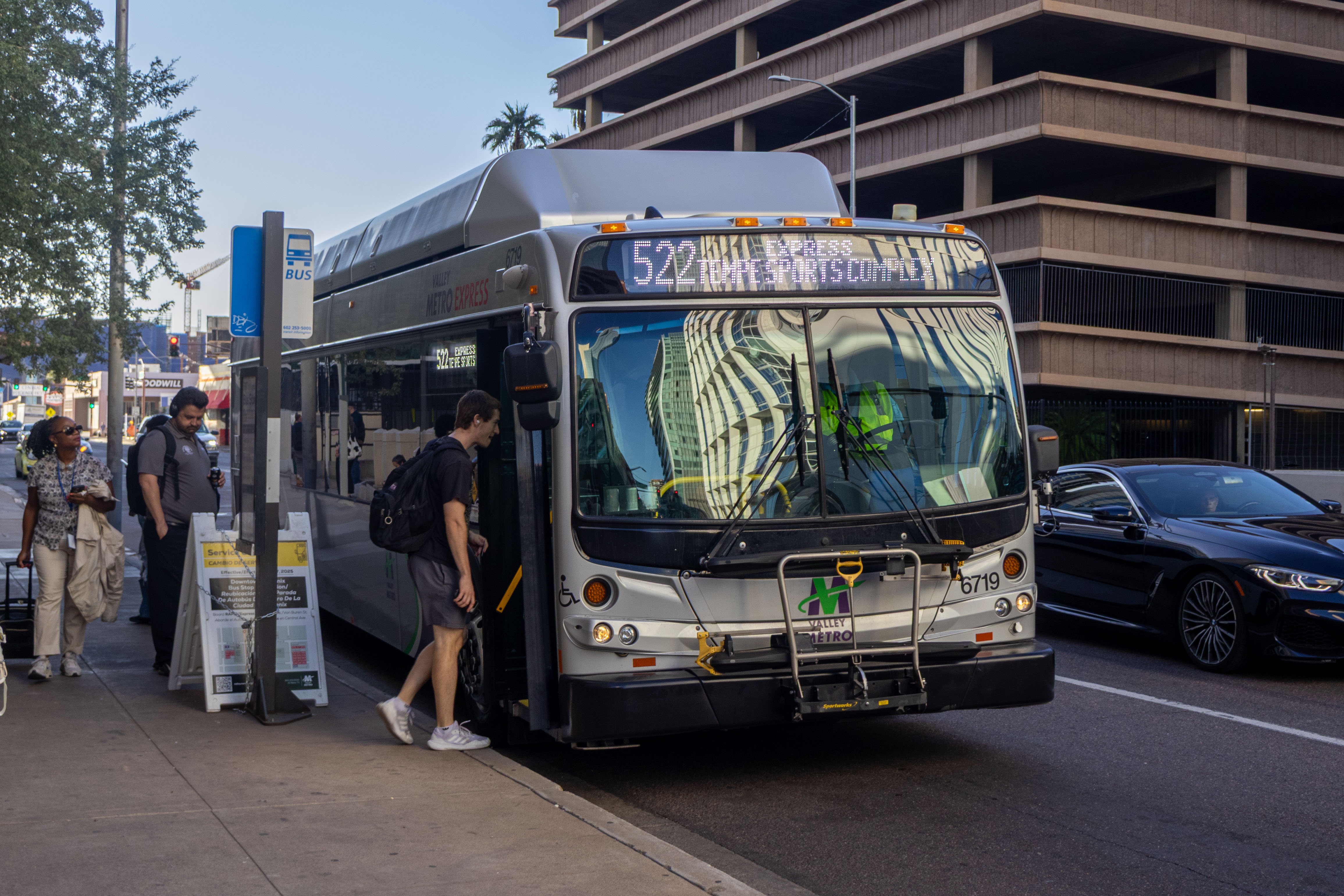 A silver Valley Metro bus, with green, purple, and white stripes, number 6719, traveling eastbound on Van Buren Street in Phoenix on route 522 to Tempe Sports Complex