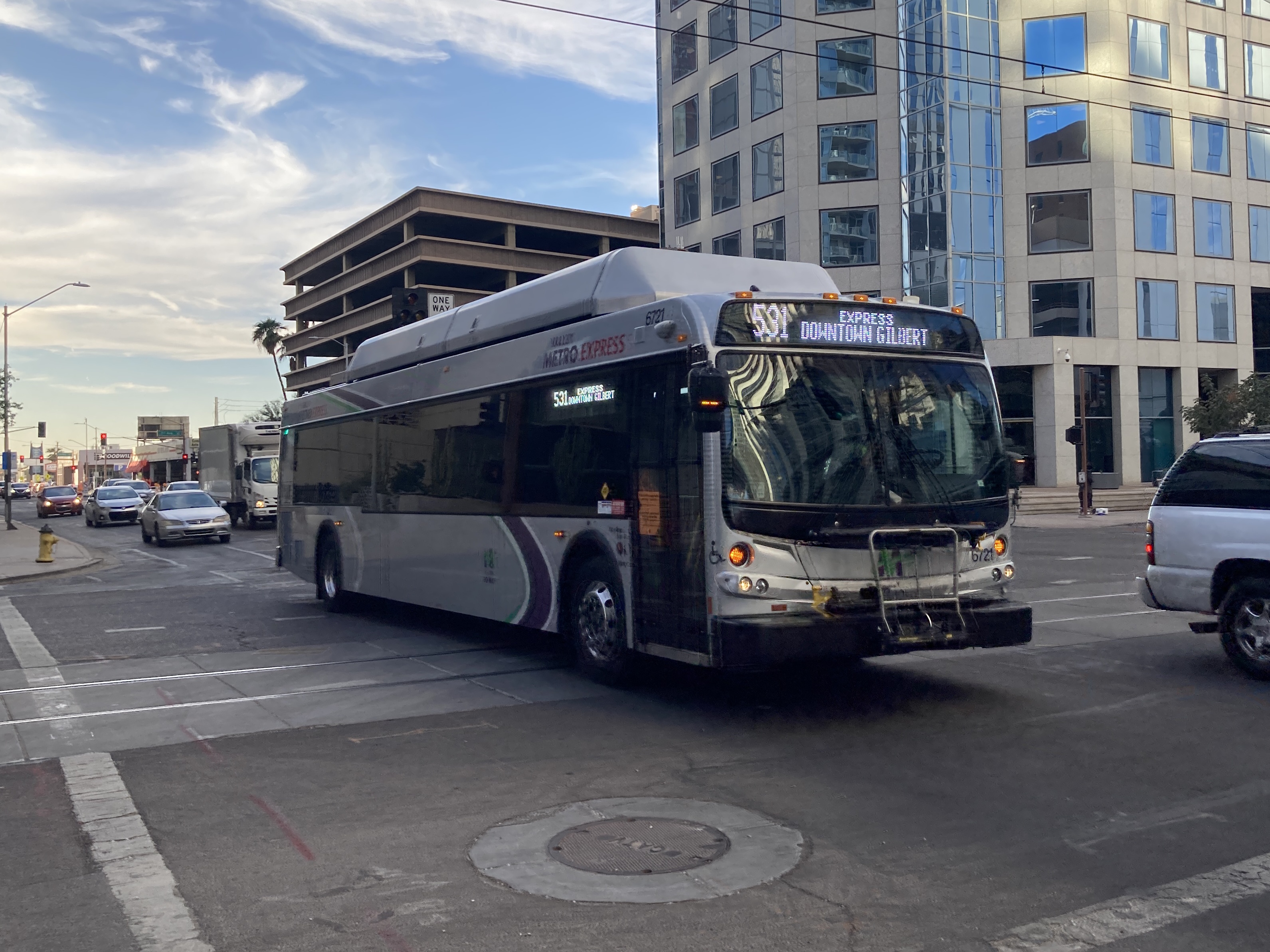 A silver Valley Metro bus, with green, purple, and white stripes, number 6721, traveling eastbound on Van Buren Street in Phoenix on route 531 to Downtown Gilbert