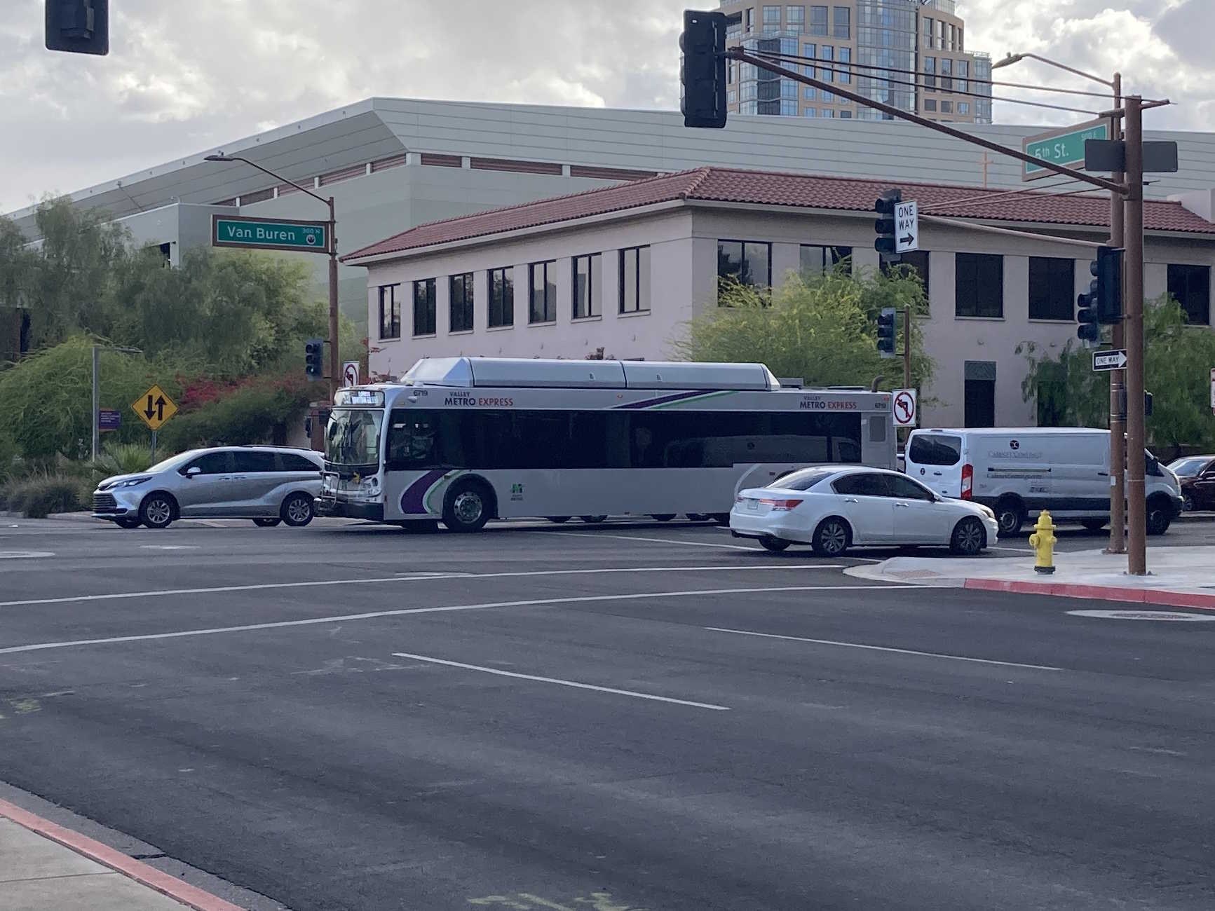 A silver Valley Metro bus, with green, purple, and white stripes, number 6719, traveling eastbound on Van Buren Street in Phoenix on route 531 to Downtown Gilbert