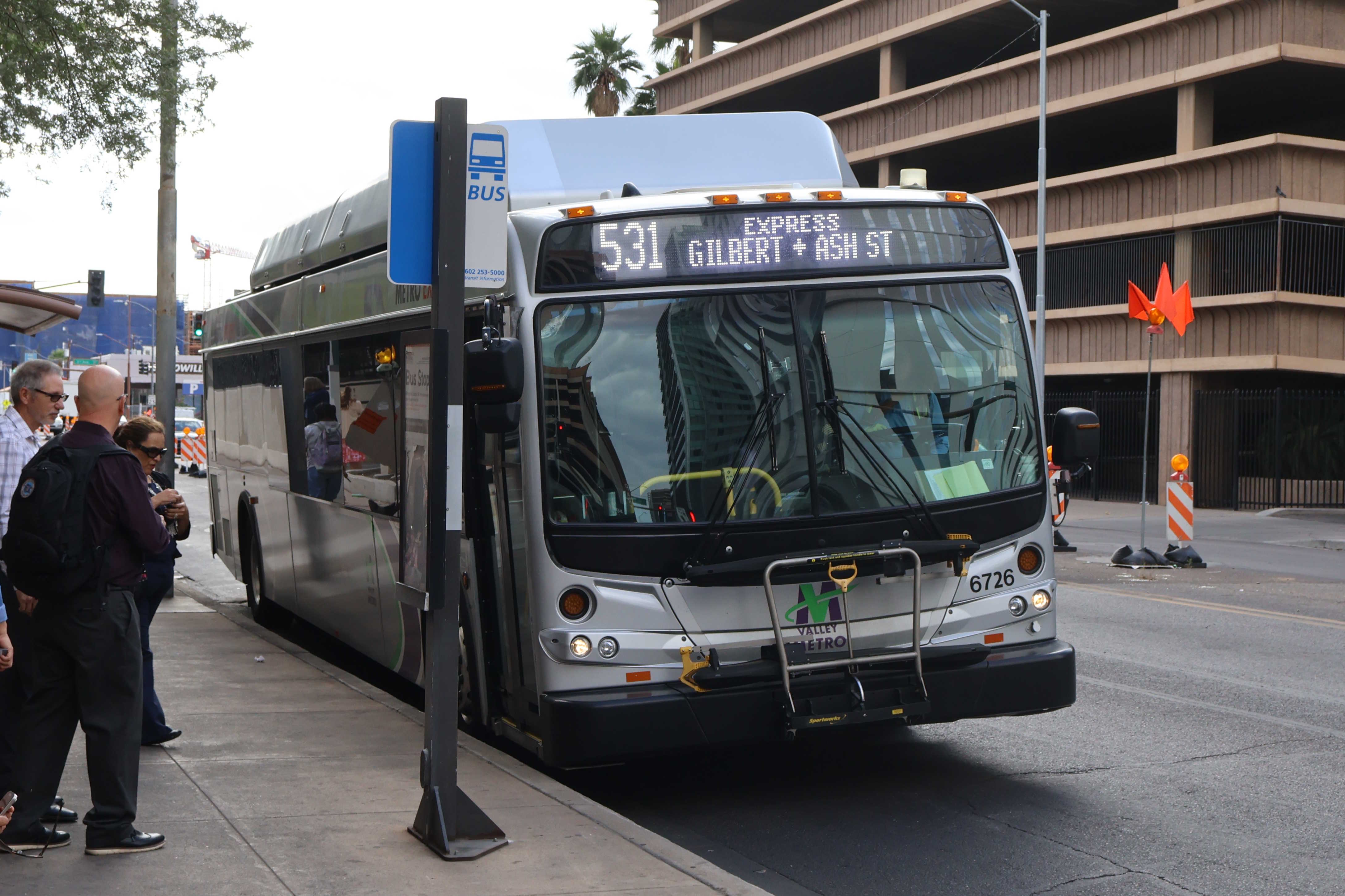 A silver Valley Metro bus, with green, purple, and white stripes, number 6726, traveling eastbound on Van Buren Street in Phoenix on route 531 to Gilbert Road and Ash Street