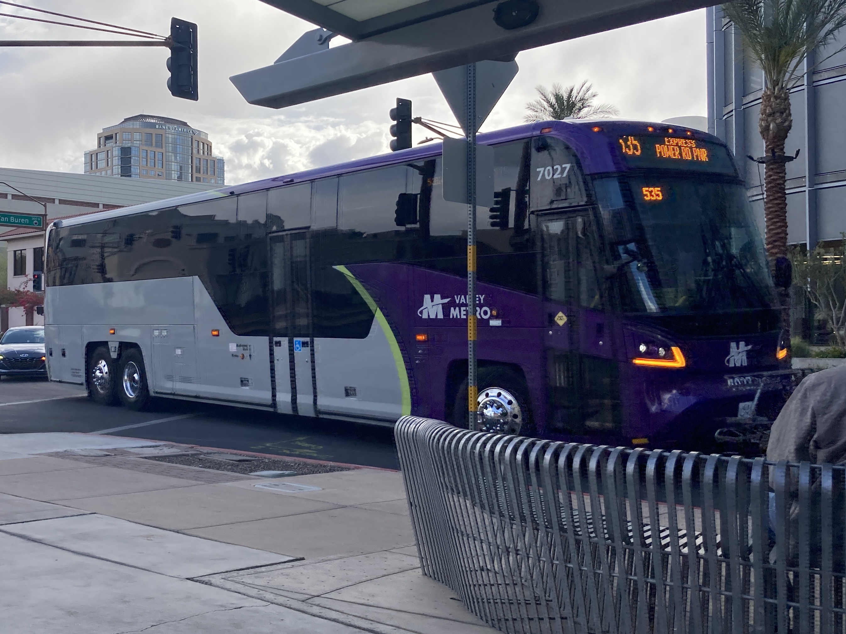 A gray and purple Valley Metro bus, with a green stripe, number 7027, traveling northbound on 5th Street in Phoenix on route 535 to Power Road Park and Ride