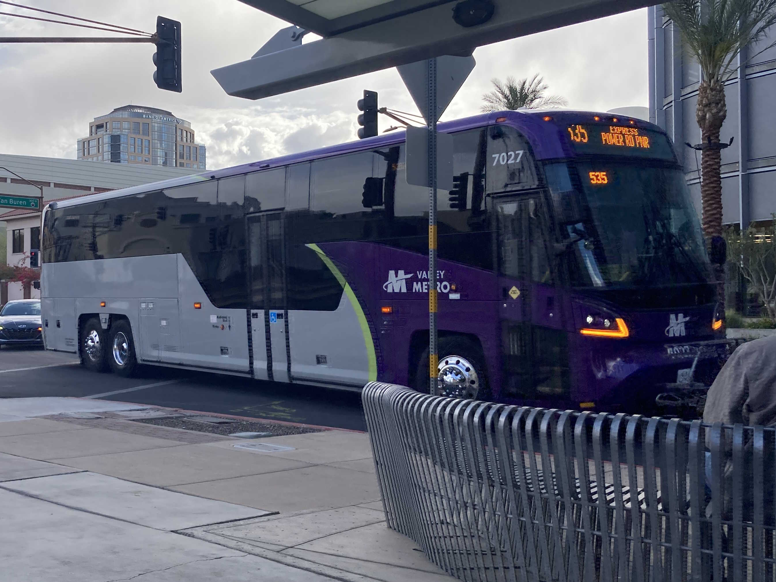 A gray and purple Valley Metro bus, with a green stripe, number 7027, traveling northbound on 5th Street in Phoenix on route 535 to Power Road Park and Ride