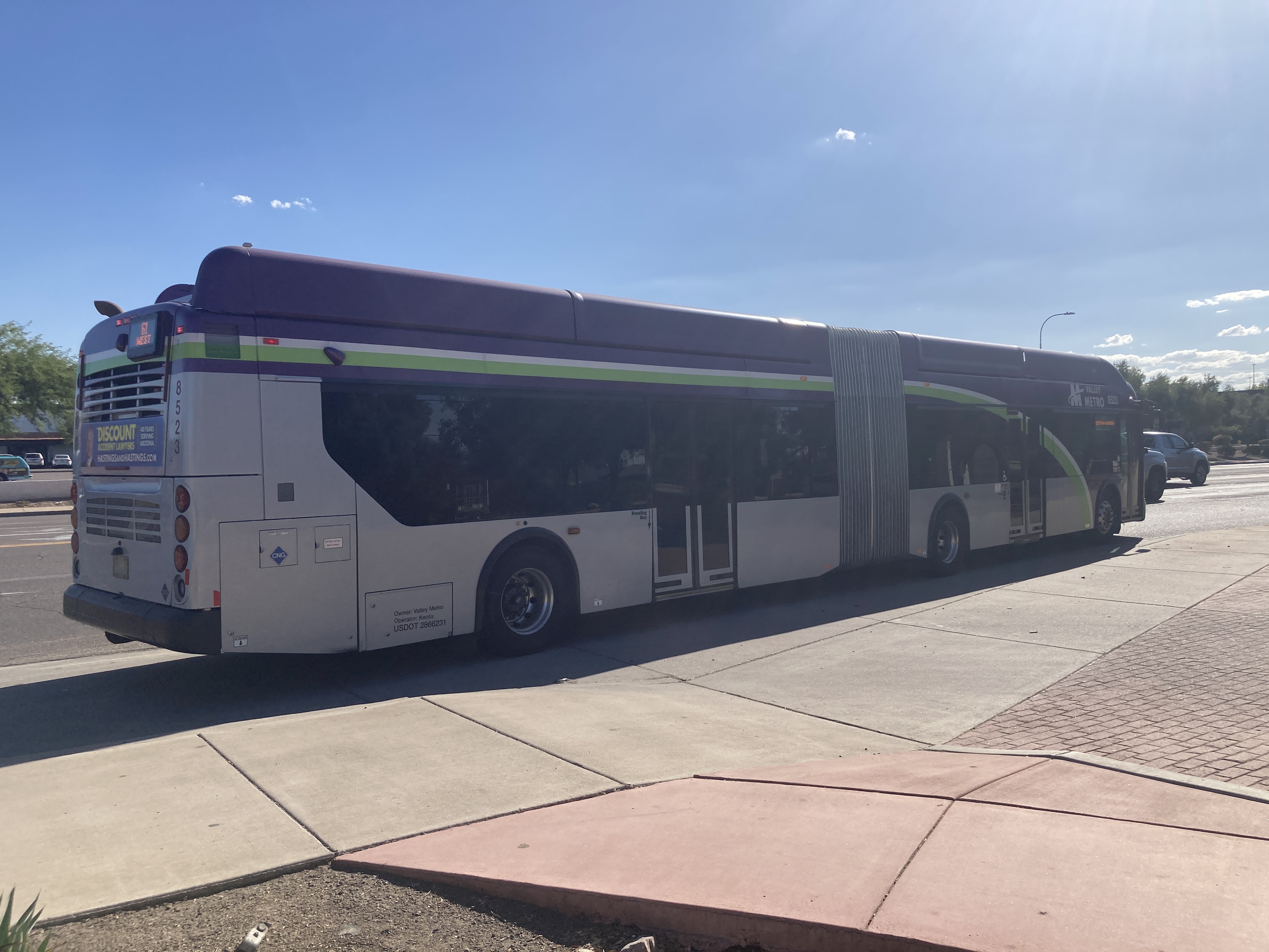 A gray and purple articulated Valley Metro bus with a green and white stripe, number 8523, traveling westbound on Southern Avenue on route 61 to Southern Avenue & 51st Avenue