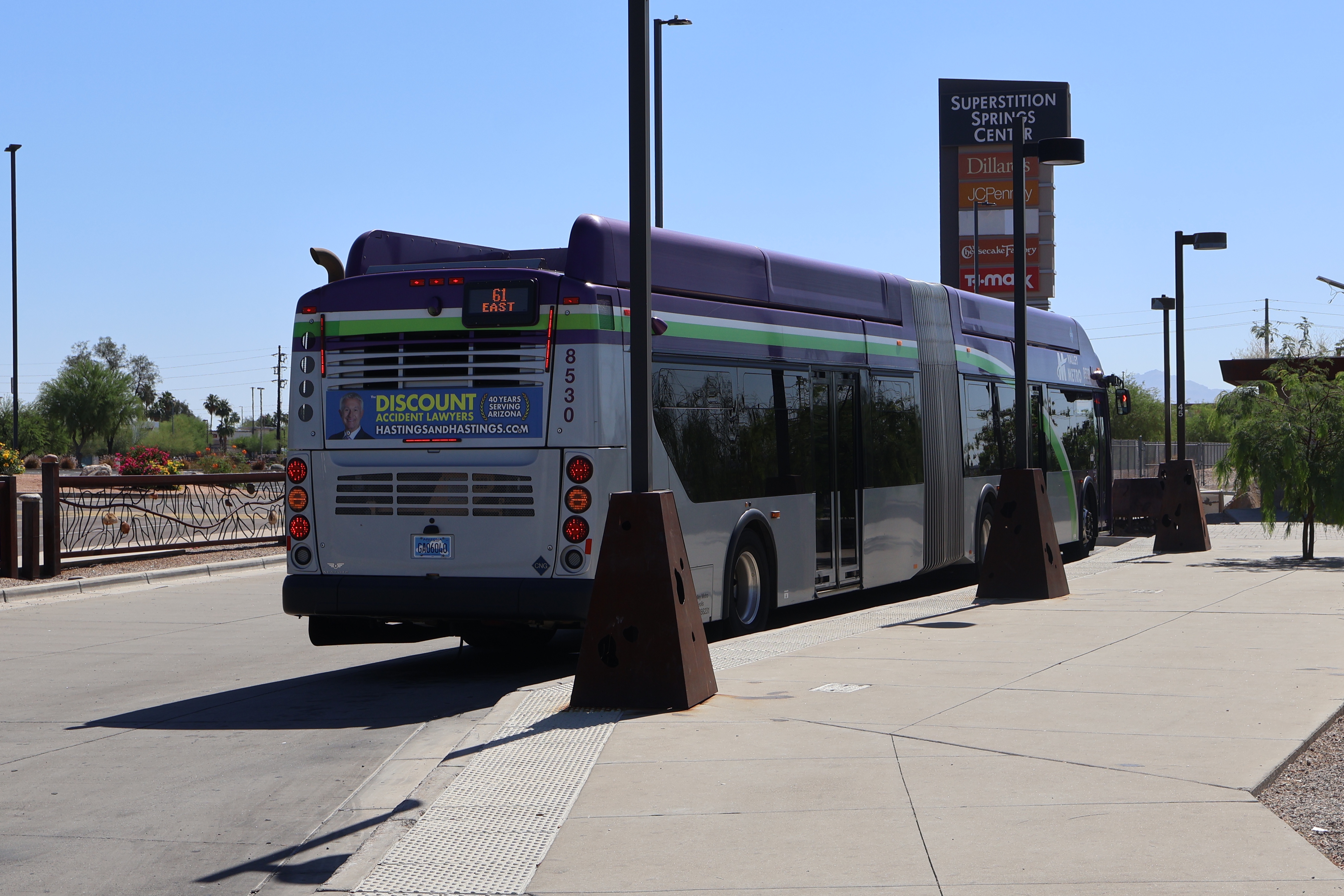 A gray and purple articulated Valley Metro bus with a green and white stripe, number 8530, at Superstition Springs Transit Center in Mesa on route 61 to Superstition Springs Transit Center