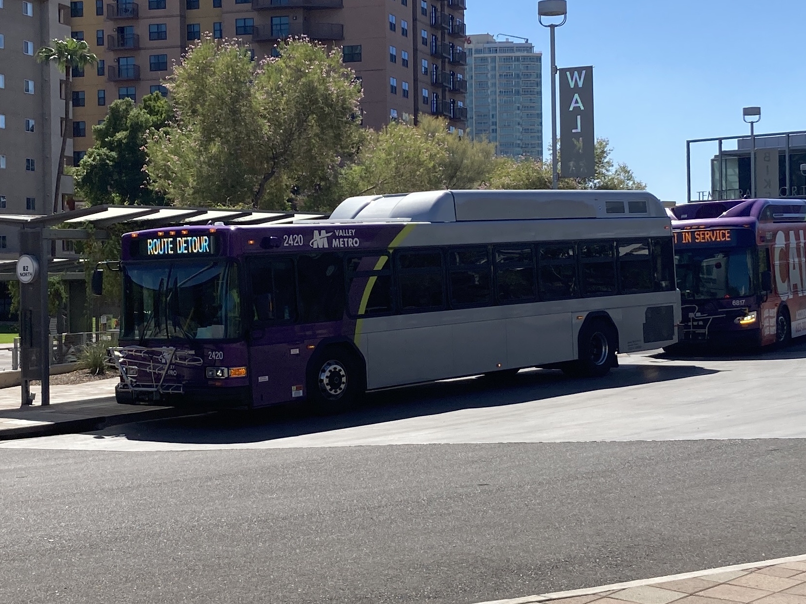 A gray and purple Valley Metro bus, with a green stripe, number 2420, at the Tempe Transportation Center, traveling route 62 to Tempe Marketplace