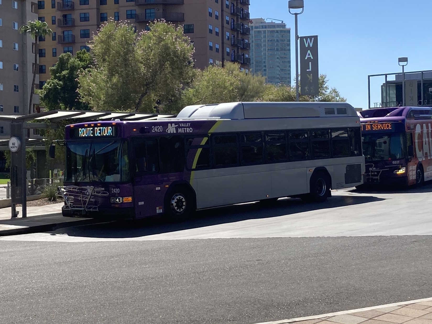 A gray and purple Valley Metro bus, with a green stripe, number 2420, at the Tempe Transportation Center, traveling route 62 to Tempe Marketplace