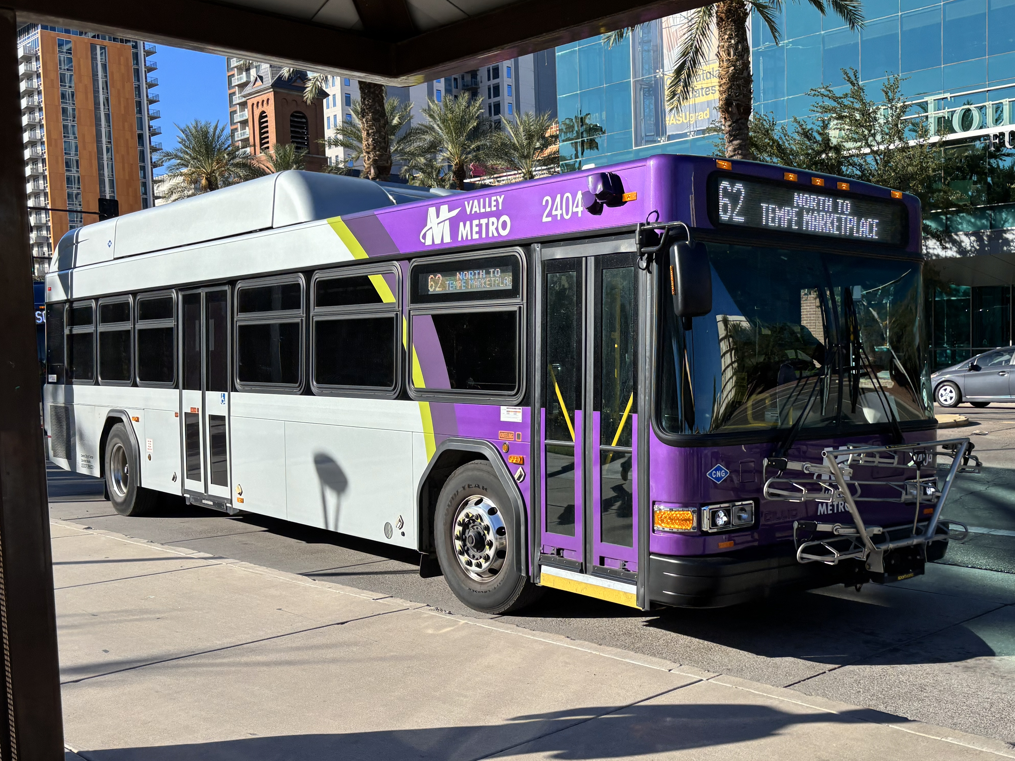 A gray and purple Valley Metro bus, with a green stripe, number 2404, traveling eastbound on University Drive on route 62 to Tempe Marketplace
