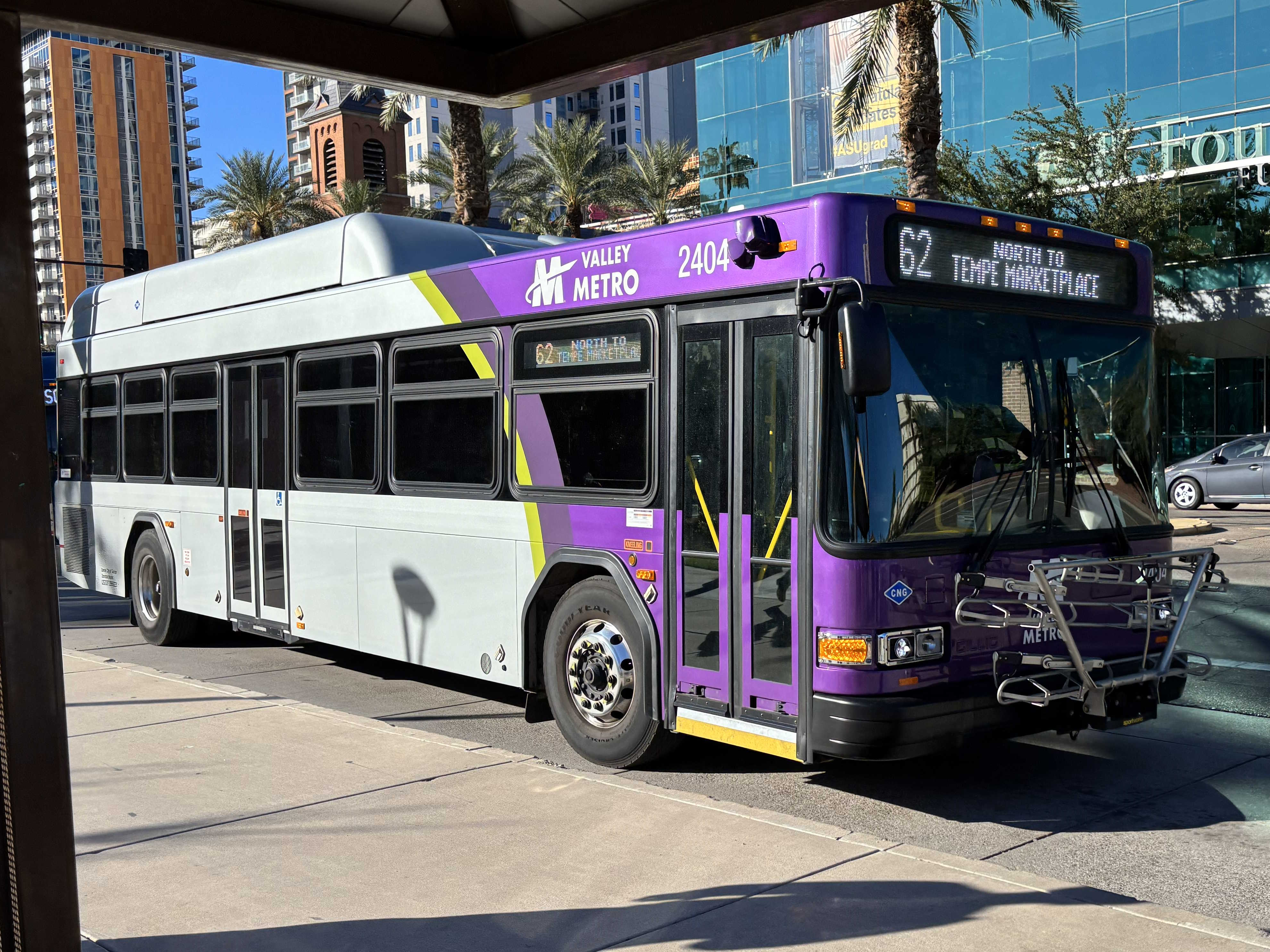 A gray and purple Valley Metro bus, with a green stripe, number 2404, traveling eastbound on University Drive on route 62 to Tempe Marketplace