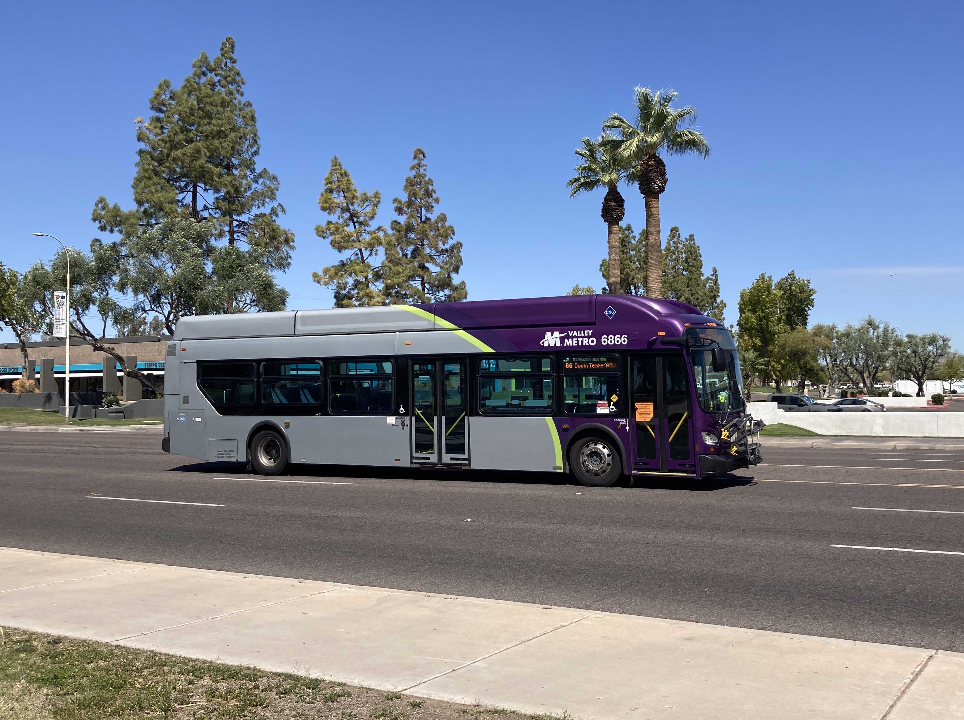 A gray, green, and purple Valley Metro bus, number 6866, traveling eastbound on Baseline Road in Tempe on route 66 to Downtown Tempe / ASU