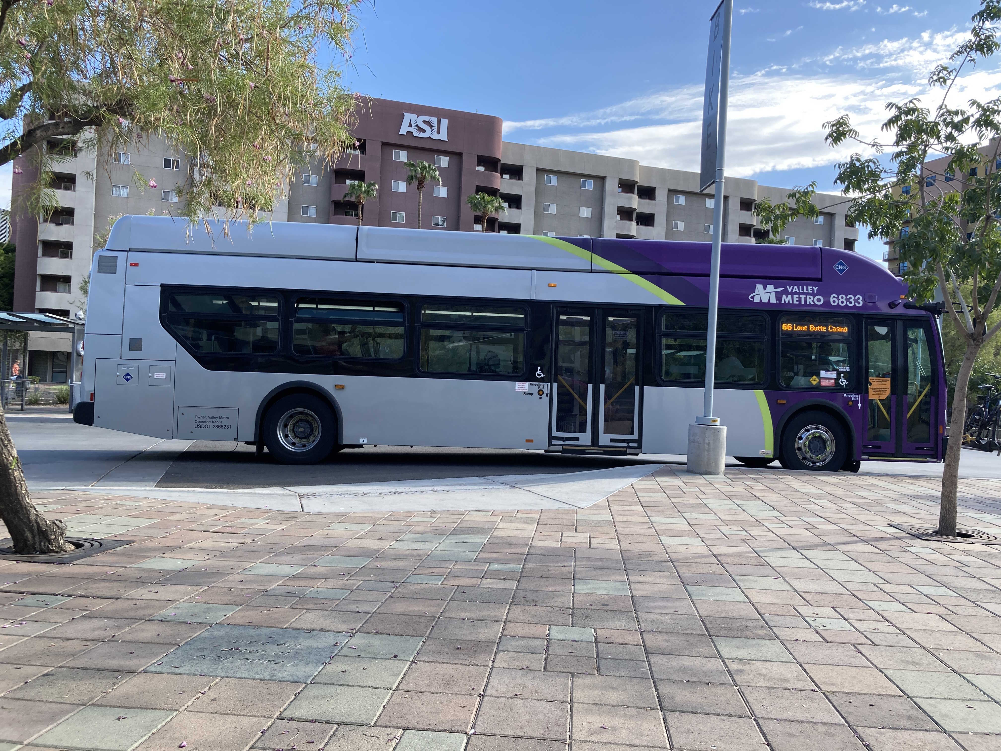 A gray, green, and purple Valley Metro bus, number 6833, at the Tempe Transportation Center, the beginning of route 66 to Lone Butte Casino