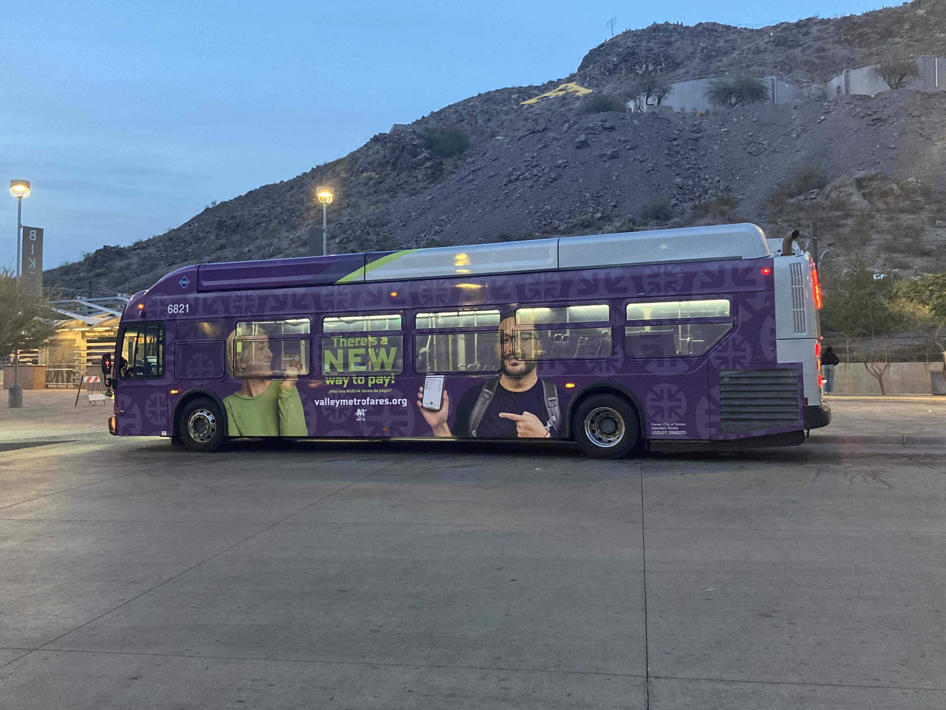 A gray, green, and purple Valley Metro bus, number 6821, at the Tempe Transportation Center, the beginning of route 66 to Kyrene Road and Elliot Road