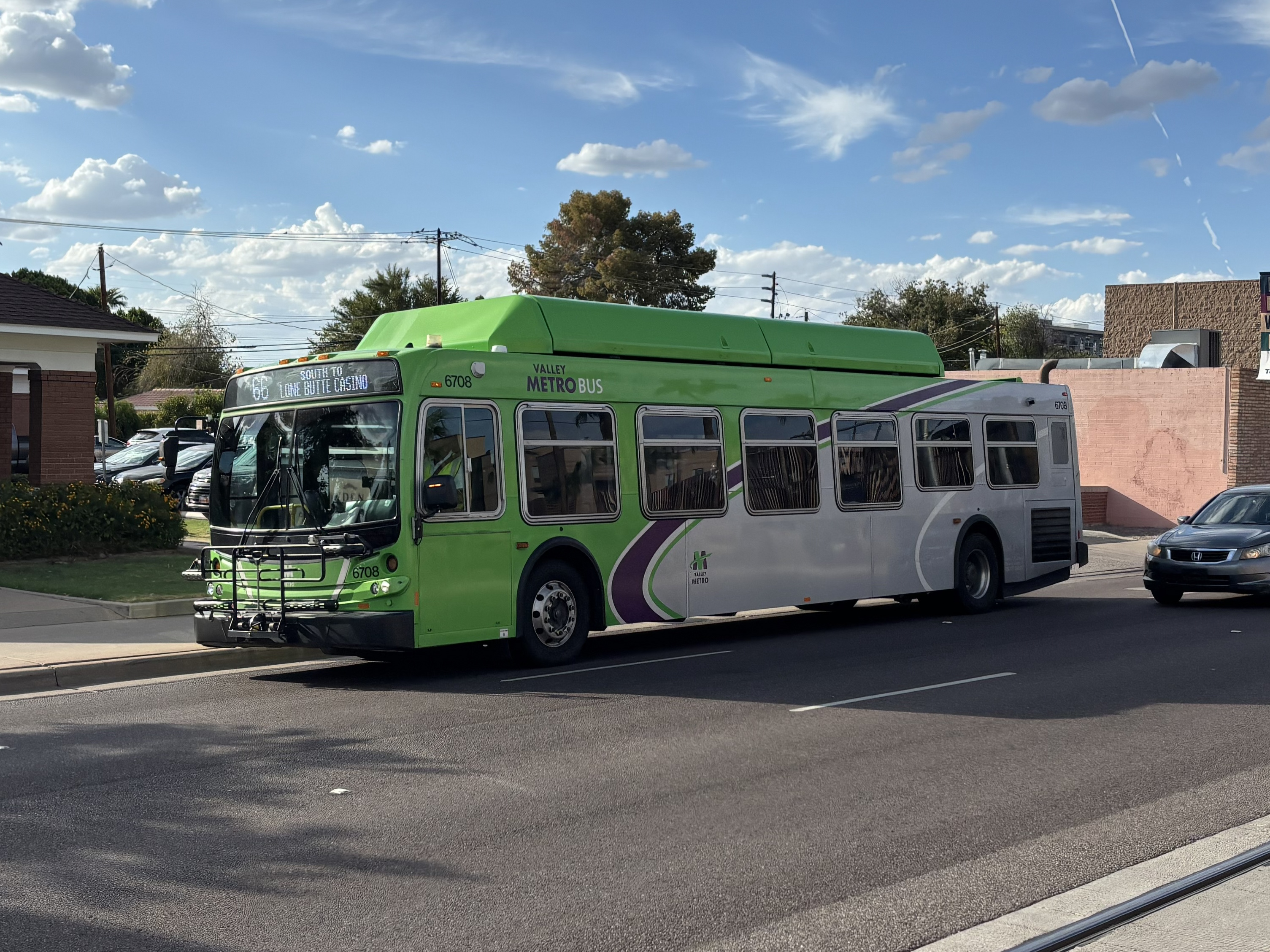 A green Valley Metro bus with a purple and white stripe, number 6708, traveling southbound on Mill Avenue in Tempe on route 66 to Lone Butte Casino