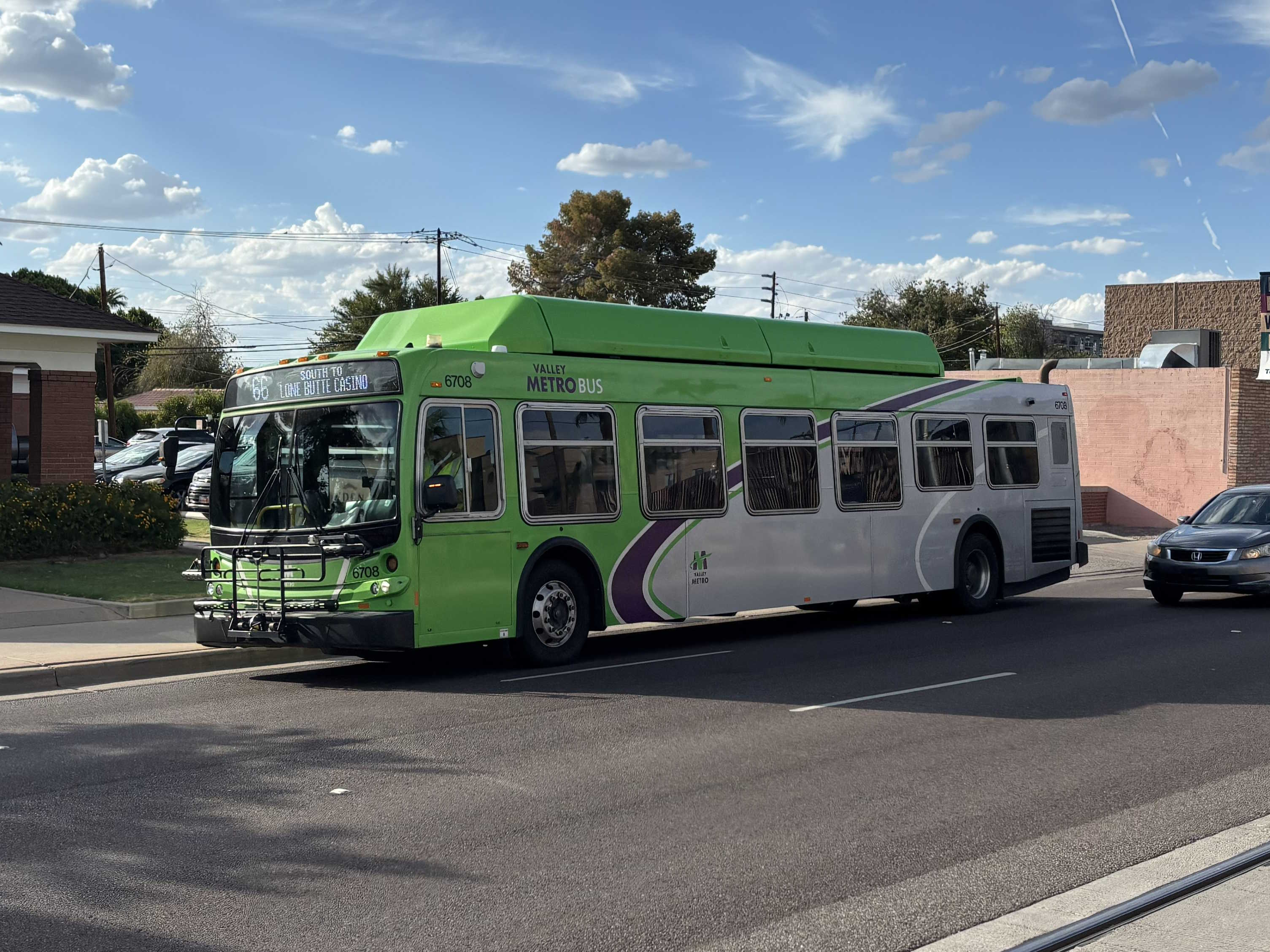 A green Valley Metro bus with a purple and white stripe, number 6708, traveling southbound on Mill Avenue in Tempe on route 66 to Lone Butte Casino