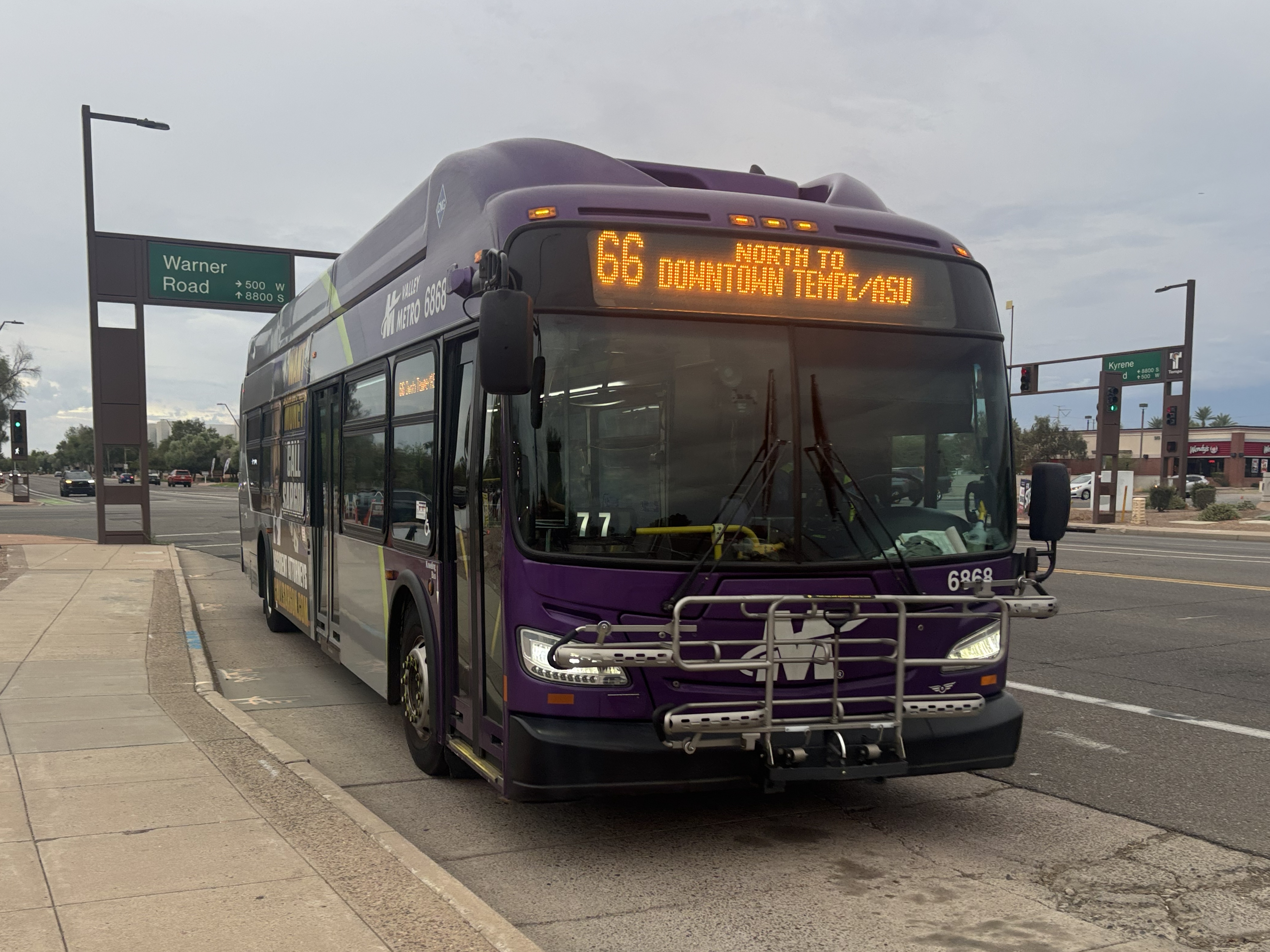 A gray and purple Valley Metro bus, with a green stripe, number 6868, traveling northbound on Mill Avenue in Tempe on route 66 to Downtown Tempe / ASU